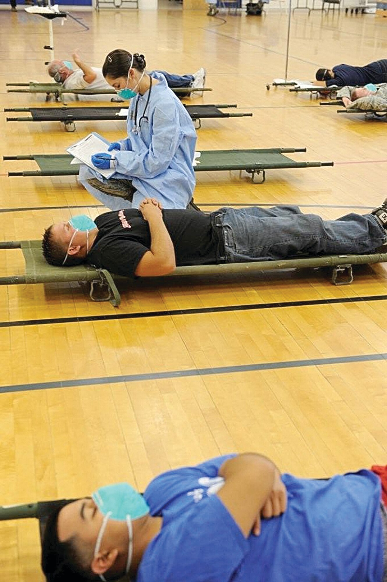 Airman 1st Class Carol McLaughlin, of the 75th MDOS, looks at a patient as others lie nearby waiting their turn.