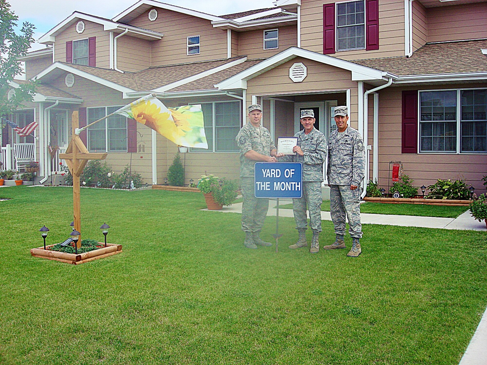 MINOT AIR FORCE BASE, N.D. -- Master Sgt. Christopher Warsitz, 5th Civil Engineer Squadron poses for a photo with Colonel James Gallagher, 5th Mission Support Group commander and Chief Master Sgt. John Hemmy, 5th MSG superintendant. Sergeant Warsitz's meticulously maintained residence earned him yard of the month for August. Sergeant Warsitz received a $100.00 saving bond from the Minot Chapter of the Air Force Association, a $10.00 gift card from AAFES, and $15.00 in Darby Dollars to spend in 5th Force Support Squadron facilities. (courtesy photo)
