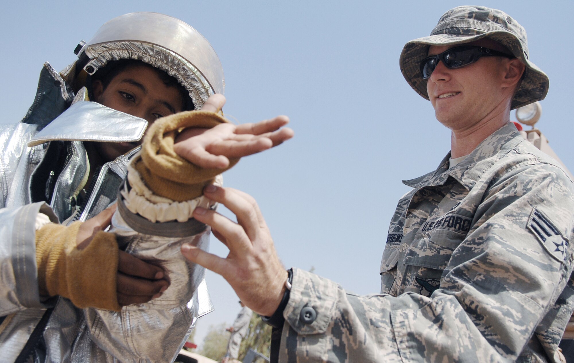 Senior Airman Kevin Andrews helps an Iraqi child put on a firesuit Aug. 22 during a health fair at Joint Base Balad, Iraq.  More than 30 Iraqi children attended the health fair. Airman Andrews is a firefighter assigned to the 332nd Expeditionary Civil Engineer Squadron. (U.S. Air Force photo/Senior Airman Christopher Hubenthal)