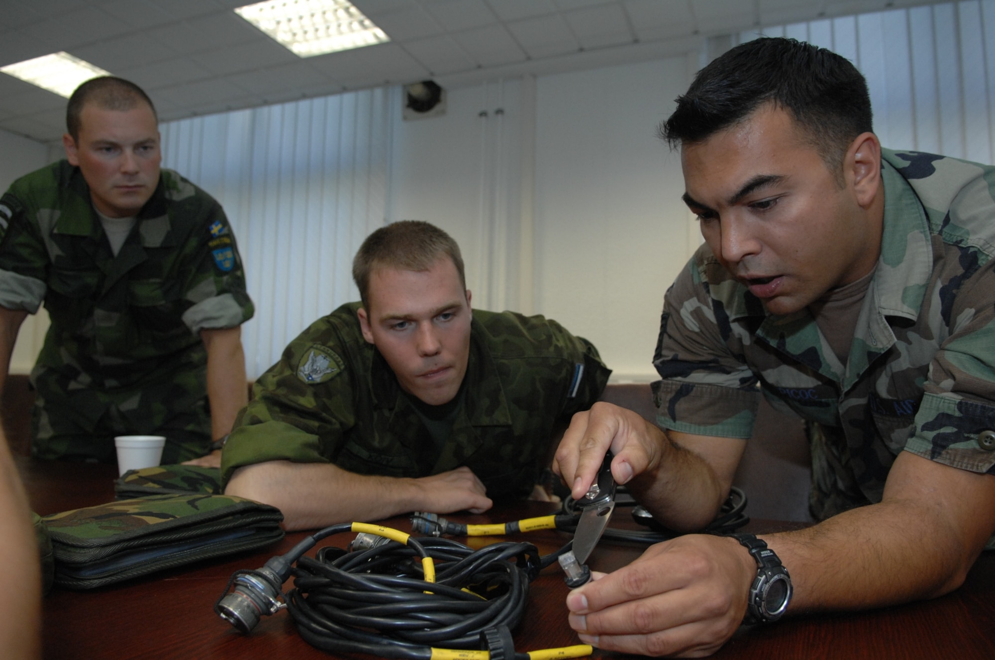 RAMSTEIN AIR BASE, Germany- Tech. Sgt. Nicholas Picoc (right), who is in charge of training and evaluations at the U.S. Air Forces in Europe Air Ground Operations School, briefs international forward air controllers on upgrades to the ROVER III, a kit which mainly consists of a tactical laptop, antennas, cables and other items used to receive live video feed from aircraft during close air support operations.  Two Estonian air force members and a Swedish army ranger spent a week in pre-deployment briefings, computer simulation, and field training prior to deployment thanks to the joint efforts of the staff at the USAFE AGOS and the International Security Assistance Force Cell at NATO Allied Air Component Command Headquarters Ramstein Aug. 17- 21. (U.S. Air Force photo/Master Sgt. Corey Clements)