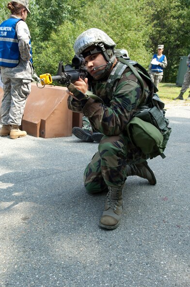 HANSCOM AIR FORCE BASE, Mass. – Senior Airman Robert Rivera, 66th Security Forces Squadron takes up a defensive position during a Base Readiness Exercise at Camp Patriot on Aug. 20. Exercise Evaluation Team members are shown in the background evaluating the readiness skills of participants following a simulated attack. (U.S. Air Force photo by Rick Berry)