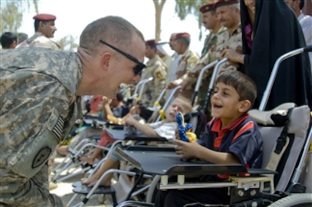 U.S. Army Capt. John Turner, of Alpha Battery, 2nd Battalion, 8th Field Artillery Regiment, interacts with an Iraqi child at Forward Operating Base Lion near Baqouba, Iraq, on Aug. 19, 2009.  U.S. soldiers helped fit the boy and six other children with wheelchairs donated by a U.S. charity.  