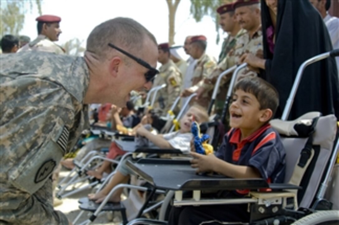 U.S. Army Capt. John Turner, of Alpha Battery, 2nd Battalion, 8th Field Artillery Regiment, interacts with an Iraqi child at Forward Operating Base Lion near Baqouba, Iraq, on Aug. 19, 2009.  U.S. soldiers helped fit the boy and six other children with wheelchairs donated by a U.S. charity.  