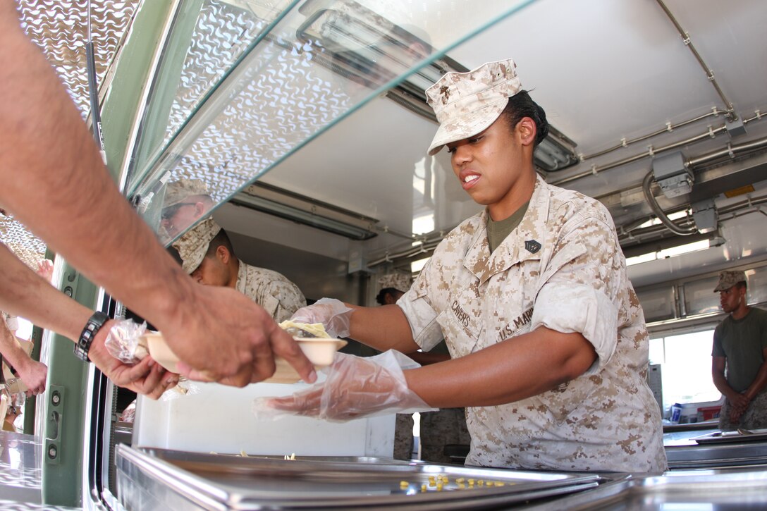 Gunnery Sgt. Cocheta L. Cavers, the Marine Wing Support Squadron 374 mess chief, serves up shredded beef to Marines and sailors from the Field Food Service System at Camp Wilson Aug. 27. The FFSS was set up for the week to serve hot food to squadron Marines training there.