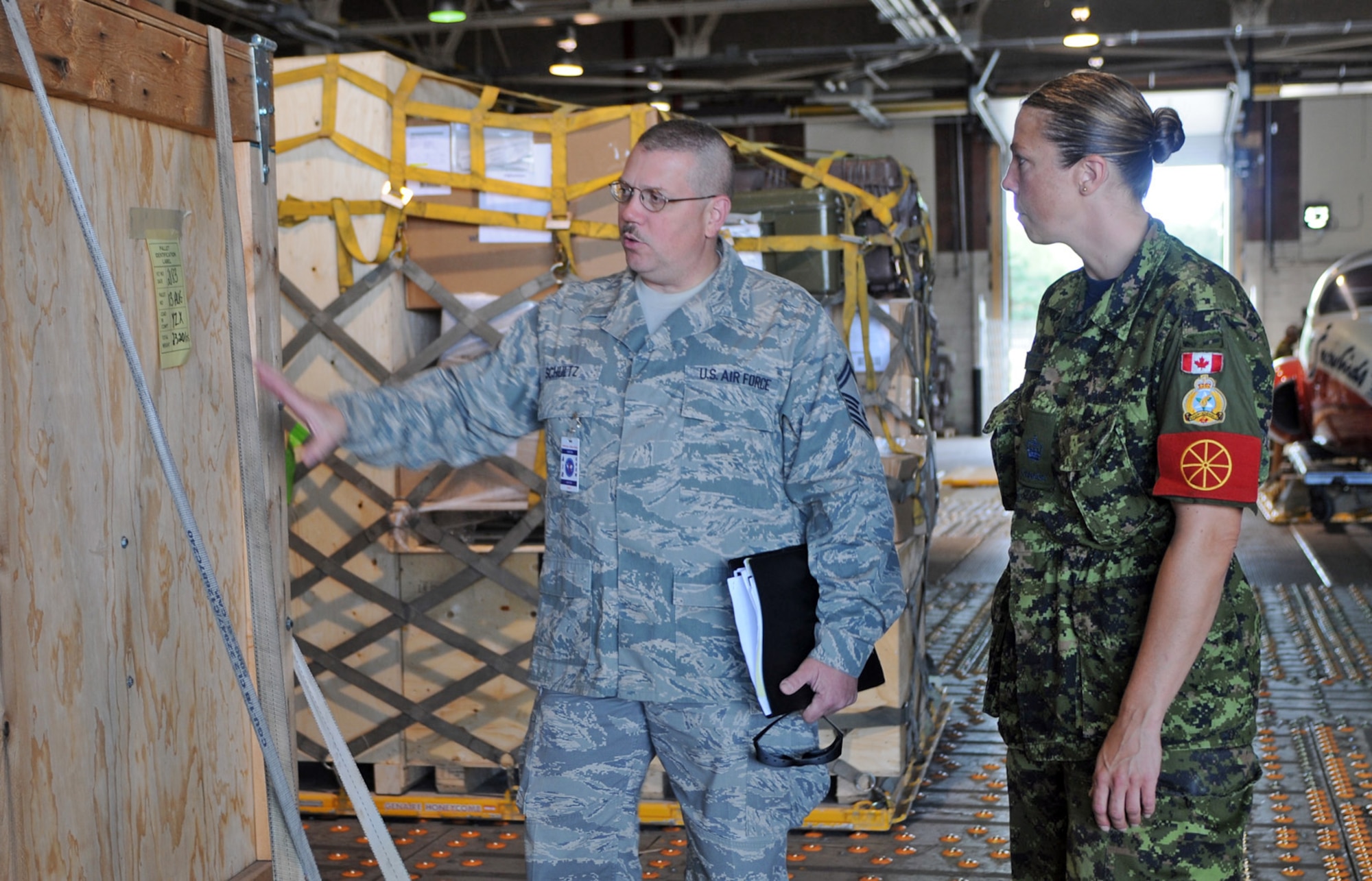 Senior Master Sgt. Dan Schultz discusses aerial port operations Aug. 24 with Canadian Royal Air Force Warrant Officer April Roach of the 2 Air Movements Squadron, a unit of the 8 Wing at Canadian Forces Base Trenton, Ontario.  Ten aircrew members from Air Force Reserve Command's 512th Airlift Wing at Dover Air Force Base, Del., flew to the Canadian base to spend three days with Royal Canadian Air Force members to forge a partnership and identify future training opportunities for flying, aerial port operations, airlift control and maintenance procedures. Sergeant Schultz is the NCO in charge of the 46th APS ramp at Dover AFB.  (U.S. Air Force photo/Capt. Marnee A.C. Losurdo)