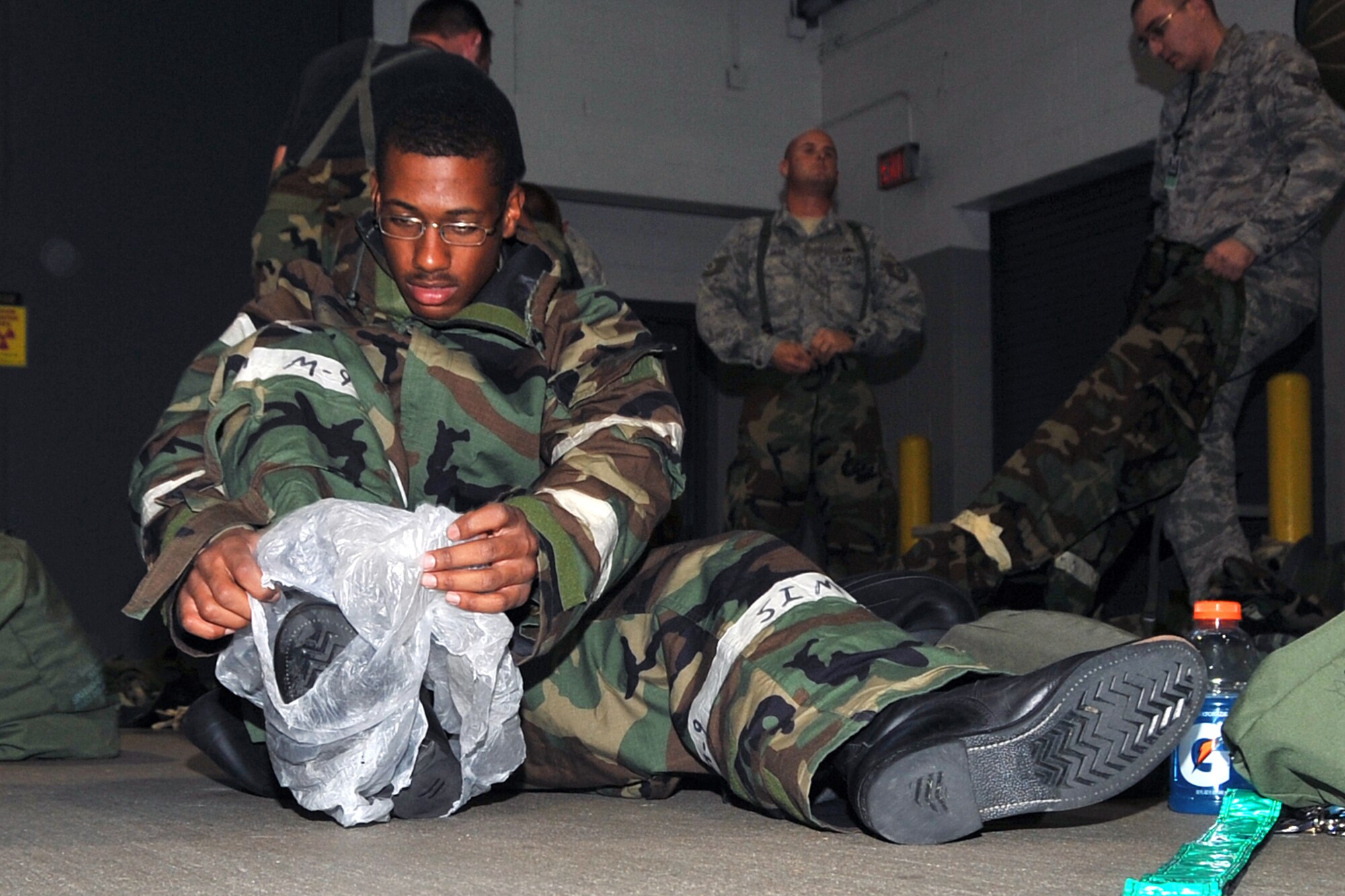 OFFUTT AIR FORCE BASE, Neb. -- Staff Sgt. Garrell Armstrong, 55th Maintenance Squadron, places plastic bags under his chemical over boots at the Bennie Davis Maintenance Facility here during an expeditionary training day Aug. 20. The training day consisted of self aid buddy care, post attack reconnaissance sweeps and the proper donning of chemical gear. U.S. Air Photo by Jeff W. Gates