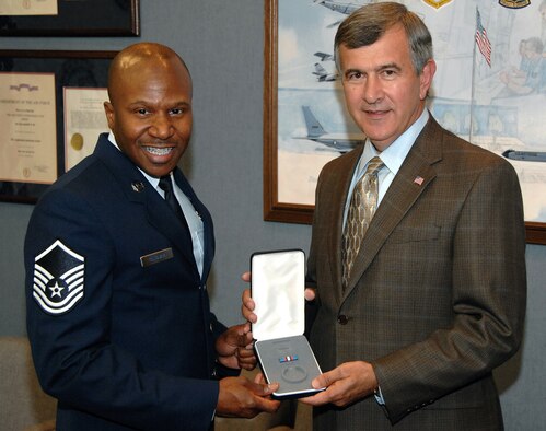 OFFUTT AIR FORCE BASE, Neb. - Mike Johanns, Nebraskan senator,  presents Master Sgt. Tyrone F. Bingham, host aviation resource manager for the 170th Operational Support Squadron here, with a medal for his selection as one of 12 Outstanding Airmen of the Year during the senator's visit to Offutt Aug. 20.U.S. Air Force photo by D.P. Heard