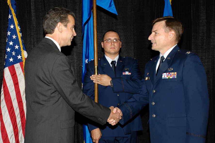 Ron Mason, director of the 653d Electronic Systems Wing, congratulates Col. Jimmie Schuman during an Aug. 26 ceremony in which the colonel assumed command of the 853d Electronic Systems Group.   The group executive officer, 1st Lt. Jason Patterson, bore and passed the guidon.  (USAF Photo by Linda LaBonte-Britt)