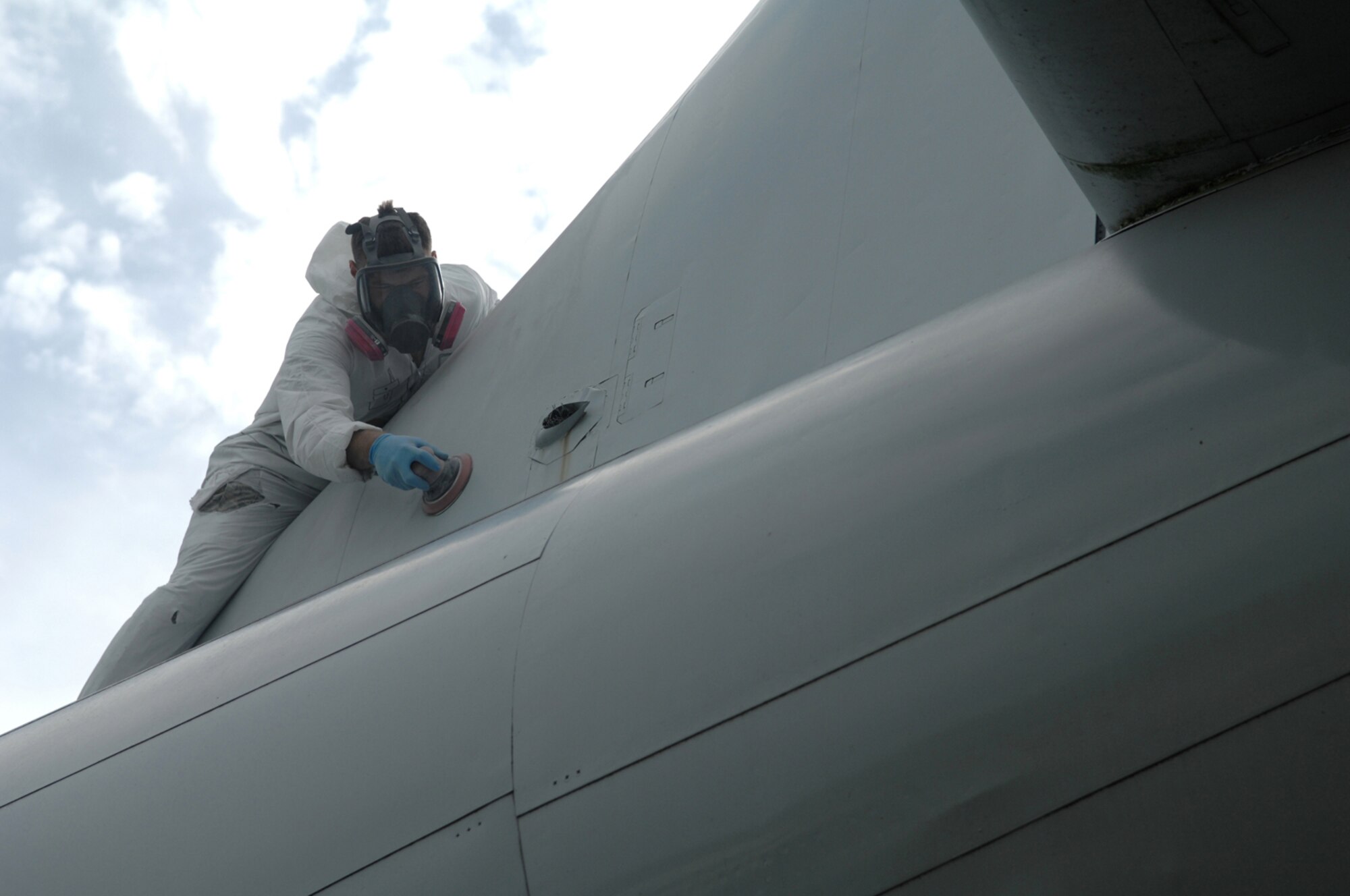 WHITEMAN AIR FORCE BASE, Mo. - Airman 1st Class Justin Pike, 509th Maintenance Squadron, uses a sander to remove old protective coating and paint on a KC-97 static display Aug. 20. Once removed members from the 509th Maintenance and Munitions squadrons will restore the protective coating, paint and perform any required sheet metal repair to the KC97 static display.  The restoration, which is required every five years, is scheduled to take a month. (U.S. Air Force photo/Senior Airman Jessica Snow)