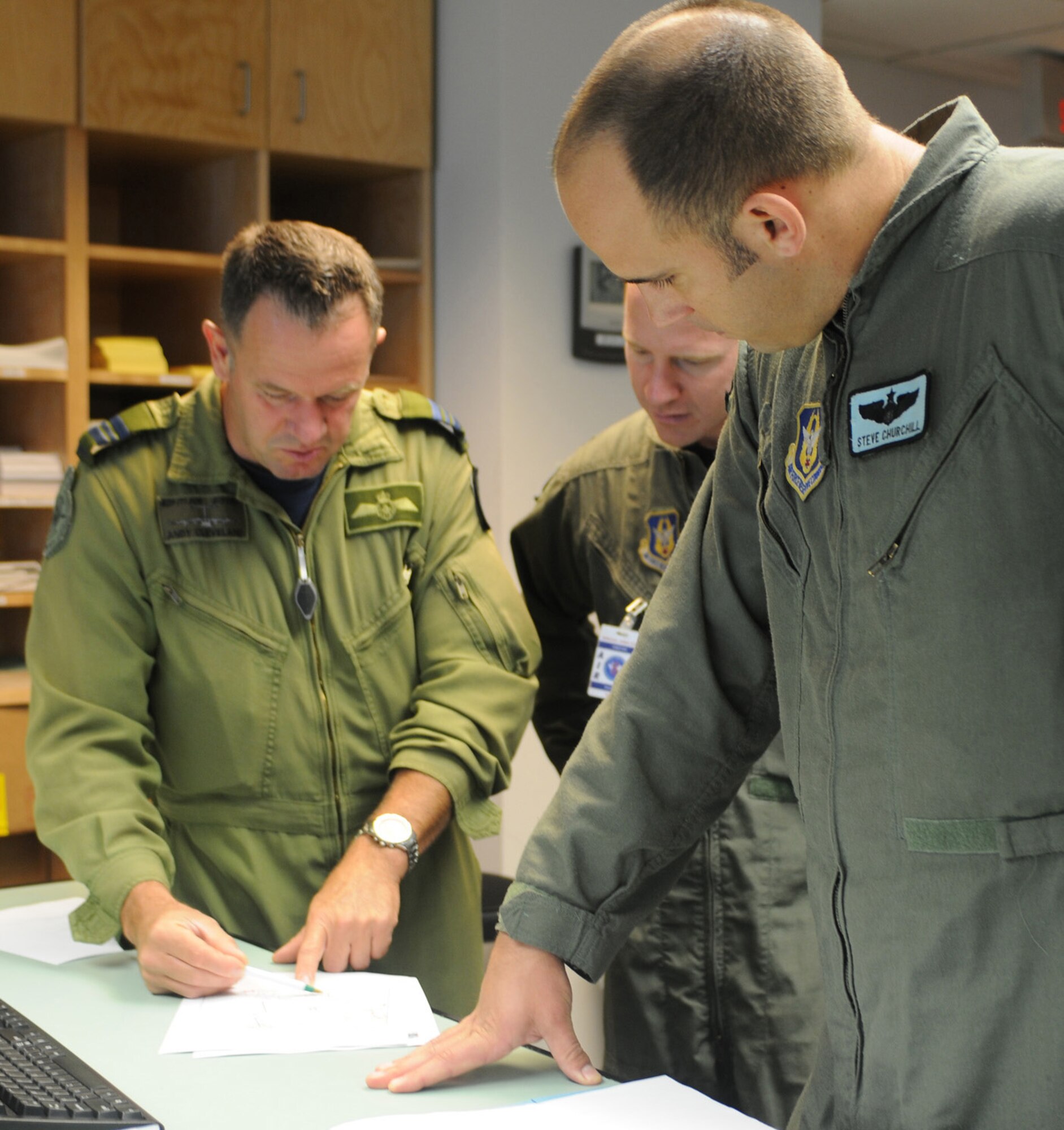 Canadian Royal Air Force Maj. Andy Cleveland, left, discusses flight plans with Capt. Steve Churchill, 326th Airlift Squadron aircraft commander, and Capt. Dan Zappe, 326th AS pilot, Aug. 23, 2009, at 8 Wing Canadian Forces Base Trenton. Air Force reservists from Dover Air Force Base, Del., traveled to Trenton in Ontario province to identify future training opportunities with the Canadians. (U.S. Air Force photo/Capt. Marnee A.C. Losurdo)