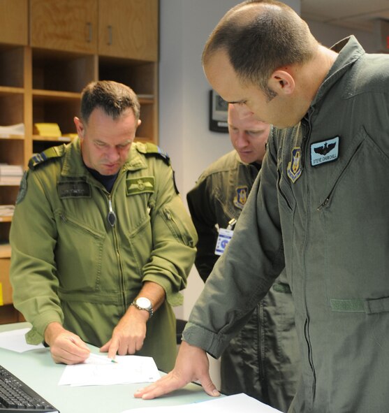 Canadian Royal Air Force Maj. Andy Cleveland, left, discusses flight plans with Capt. Steve Churchill, 326th Airlift Squadron aircraft commander, and Capt. Dan Zappe, 326th AS pilot, Aug. 23, 2009, at 8 Wing Canadian Forces Base Trenton. Air Force reservists from Dover Air Force Base, Del., traveled to Trenton in Ontario province to identify future training opportunities with the Canadians. (U.S. Air Force photo/Capt. Marnee A.C. Losurdo)