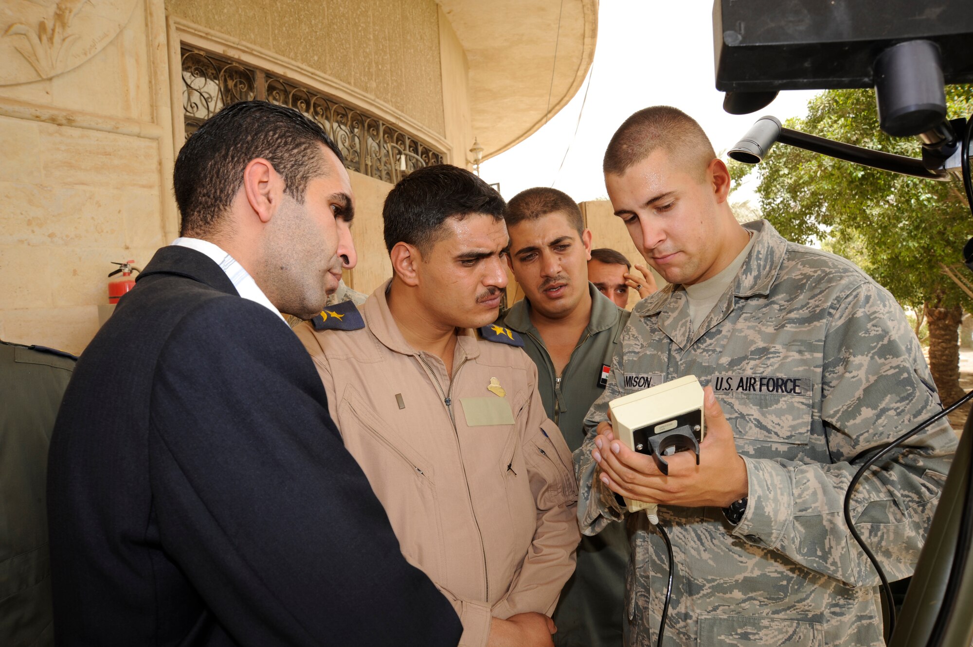 CAMP VICTORY, Iraq -- Air Force Senior Airman Daniel Jamison, weather system support cadre technician assigned to the Combined Air and Space Operations Center in Southwest Asia, teaches Iraqi air force officers how to use a handheld data display connected to a TMQ-53 tactical meteorological observation system during on-the-job training here Aug. 16, 2009. The Iraqi officers learned how to set-up, maintain and break down equipment used to obtain pressure, wind speed and direction, temperature, dew point, relative humidity, precipitation, surface visibility, cloud height and lightning detection. This system will enable the Iraqi lieutenants to provide current weather data to their leadership in support of their missions throughout Iraq. Airman Jamison is deployed from Hurlburt Field, Fla., and is a native of Troy, Mich. (U.S. Air Force photo/Tech. Sgt. Johnny L. Saldivar)