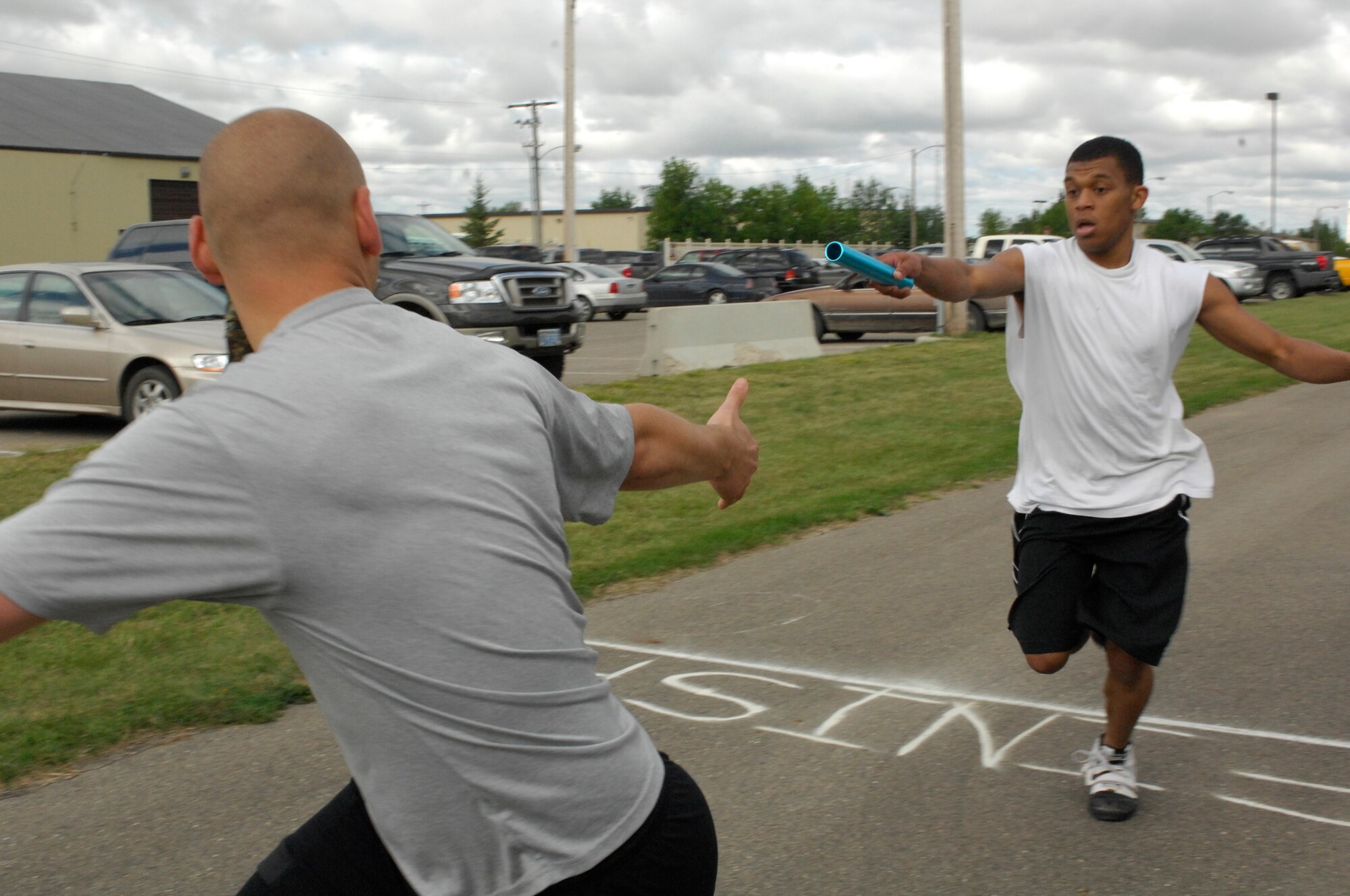 MINOT AIR FORCE BASE, N.D. -- Airman 1st Class Earl Wills, 5th Mission Support Group, client support administrator, passes the relay baton to 1st Lt. Dan McIntosh, 5th MSG, Commander’s executive, during the 4x400 relay race as part of the wing annual Summerfest here, Aug. 21. Summerfest is a morale and teambuilding program designed to test the team spirit and ingenuity of Airmen as they compete in various events for the Summerfest Championship trophy. (U.S. Air Force photo by Airman 1st Class Jesse Lopez)