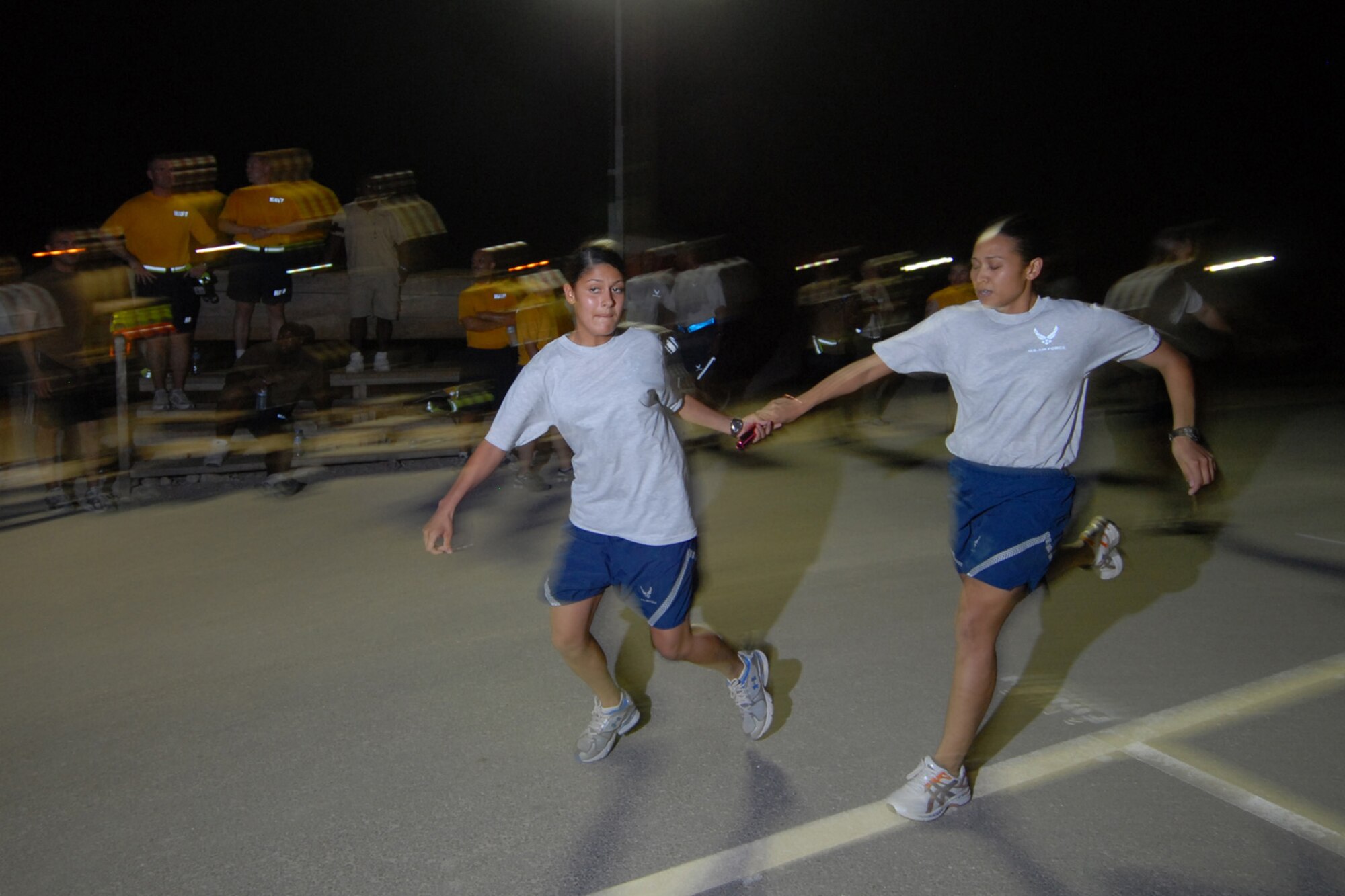 Right, Senior Airman Elain Rodriguez passes the baton to Senior Airman Katrina Oquendo, both supply journeymen assigned to the 379th Expeditionary Logistics Readiness Squadron, during the Commander?s Cup Challenge relay race event here, Aug. 25. The Commander?s Cup Challenge is a 10-event competition designed to build unit and wing esprit de corps among deployed servicemembers. Airman Rodriguez is a native of Seneca, S.C. and is deployed from Aviano Air Base, Italy. Airman Oquendo hails from Twenty Nine Palms, Calif. and is deployed from McGuire Air Force Base, N.J. Both are deployed in support of Operations Iraqi and Enduring Freedom. (U.S. Air Force Photo/Tech. Sgt. Jason W. Edwards)