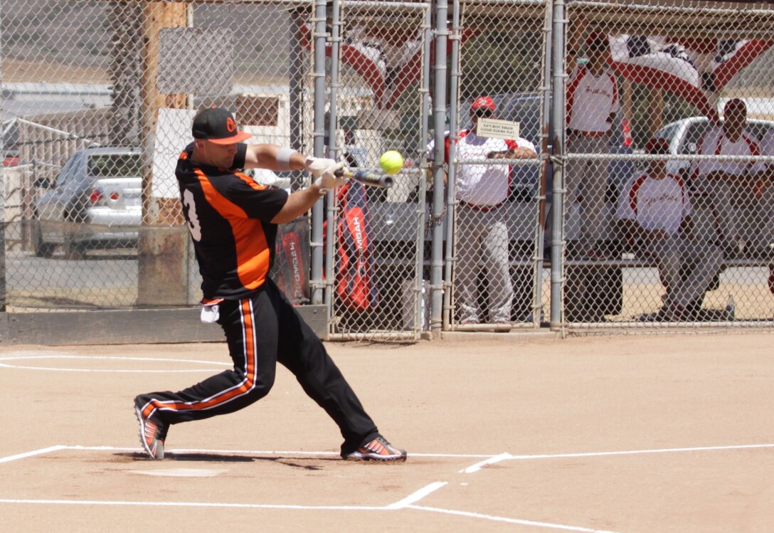 Robert Chute, Marine Corps Base, Camp Pendleton, makes contact with a softball as members of 1st Marine Logistics Group look on during the Pendleton Cup Softball Leagues’ Championship Game, which took place at the 11 Area softball field, Aug. 26.::r::::n::::r::::n::