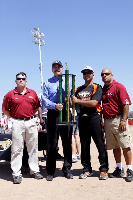 Coach Armando Delsi, Marine Corps Base softball team, stands with the Camp Pendleton athletic directors to pose for a photo with the championship trophy during the Pendleton Cup Softball Leagues' Championship Game, Aug. 26.