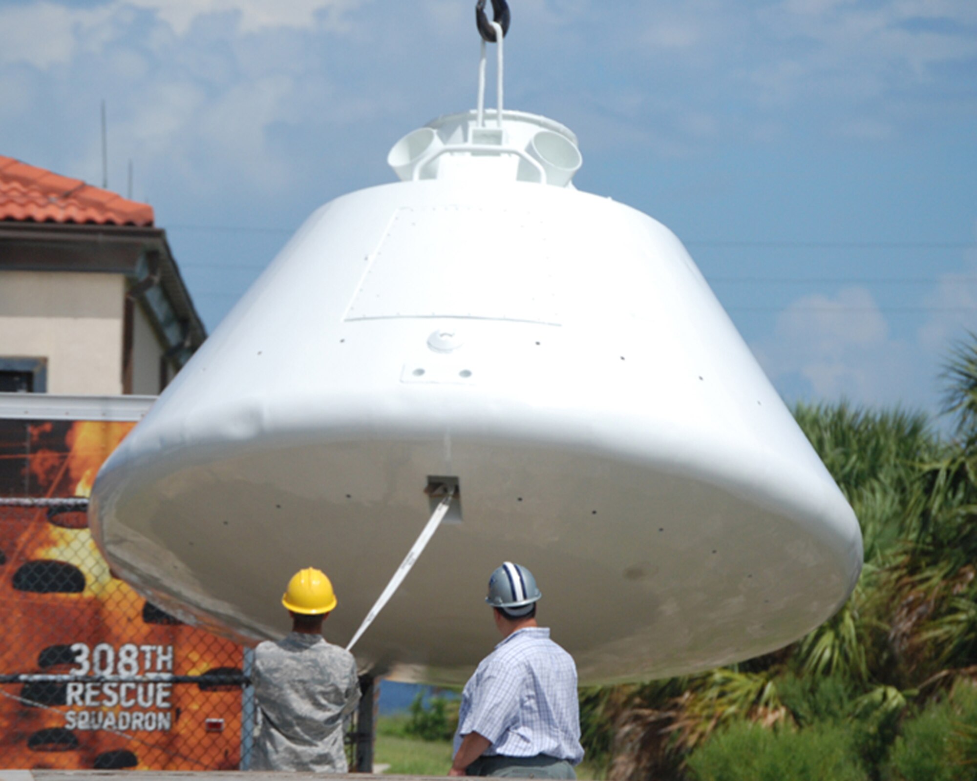 PATRICK AIR FORCE BASE, Fla. - Mr. Darrell Hankins, 920th Rescue Wing resource advisor here, oversees Staff Sgt. Billie Tyson as he directs off-loading a 9,000-pound space capsule that arrived back at the Air Force Reserve's 920th Rescue Wing from refurbishment at Excell Coatings Inc. at Port Canaveral. The capsule was used in England by U.S. Air Force Rescue personnel in the 67th Aerospace Rescue and Recovery Squadron at Royal Air Force Woodbridge to train in recovery operations for both the Apollo and Skylab programs. The capsule has been on loan from the Smithsonian Institute's National Air and Space museum to the 920th Rescue Wing since 1992. Since the 920th RQW plays a major role in space shuttle support, now and throughout history, it's a fitting display for the entrance of the pararescue squadron here. (U.S. Air Force Photo/Maj. Tricia Hill)