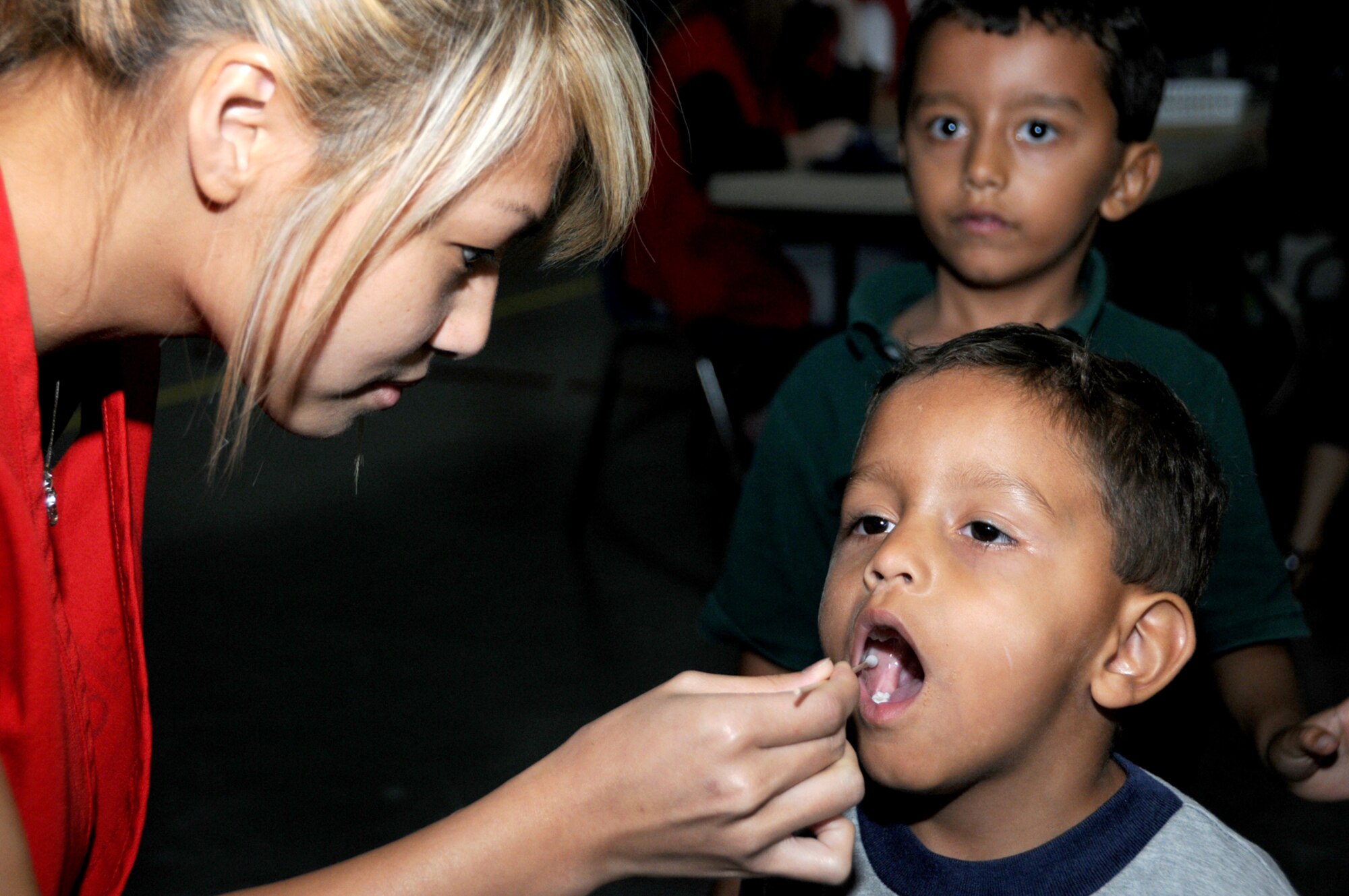 Tina Le, a volunteer from St. Martin High School, does a DNA swab on Logan Kasallis as his brother, A.J., waits his turn at the Mississippi Child Identification Program day, Saturday at the youth center.  Logan, 3, and A.J., 5, are the sons of Capt. Tony and Audrey Kasallis, 81st Dental Squadron.  Mississippi’s Freemasons have sponsored the program since 2004 to raise public awareness of the risks of child abduction and exploitation.  The DNA and a unique saliva sent can be used by tracking dogs to find missing children. (U.S. Air Force photo by Kemberly Groue)