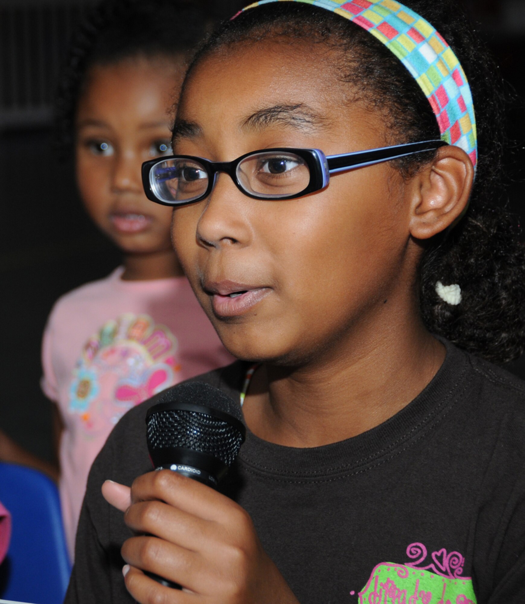 Tia Bullock, 12, speaks into a microphone for a voice recognition sample as her sister Maya Burkett, 4, looks on.  Their mom is Tech. Sgt. Christina Burkett, 336th Training Squadron.  (U.S. Air Force photo by Kemberly Groue)