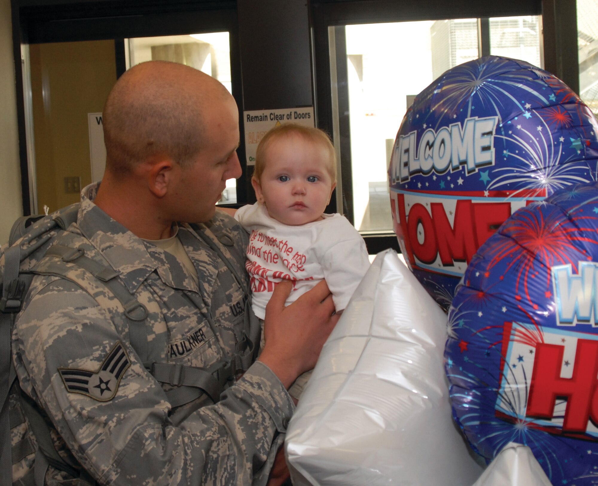 Senior Airman Michael Faulkner, 17th Security Forces Squadron, holds his daughter for the first time on Aug. 21,  after returning from a deployment with 12 of his fellow Airmen.  The 17 SFS Airmen arrived at Mathis Field, San Angelo, after an eight-month deployment to Iraq which included two months of combat skills training at Fort Dix, N.J..  (U.S. Air Force  by Robert D. Martinez).
