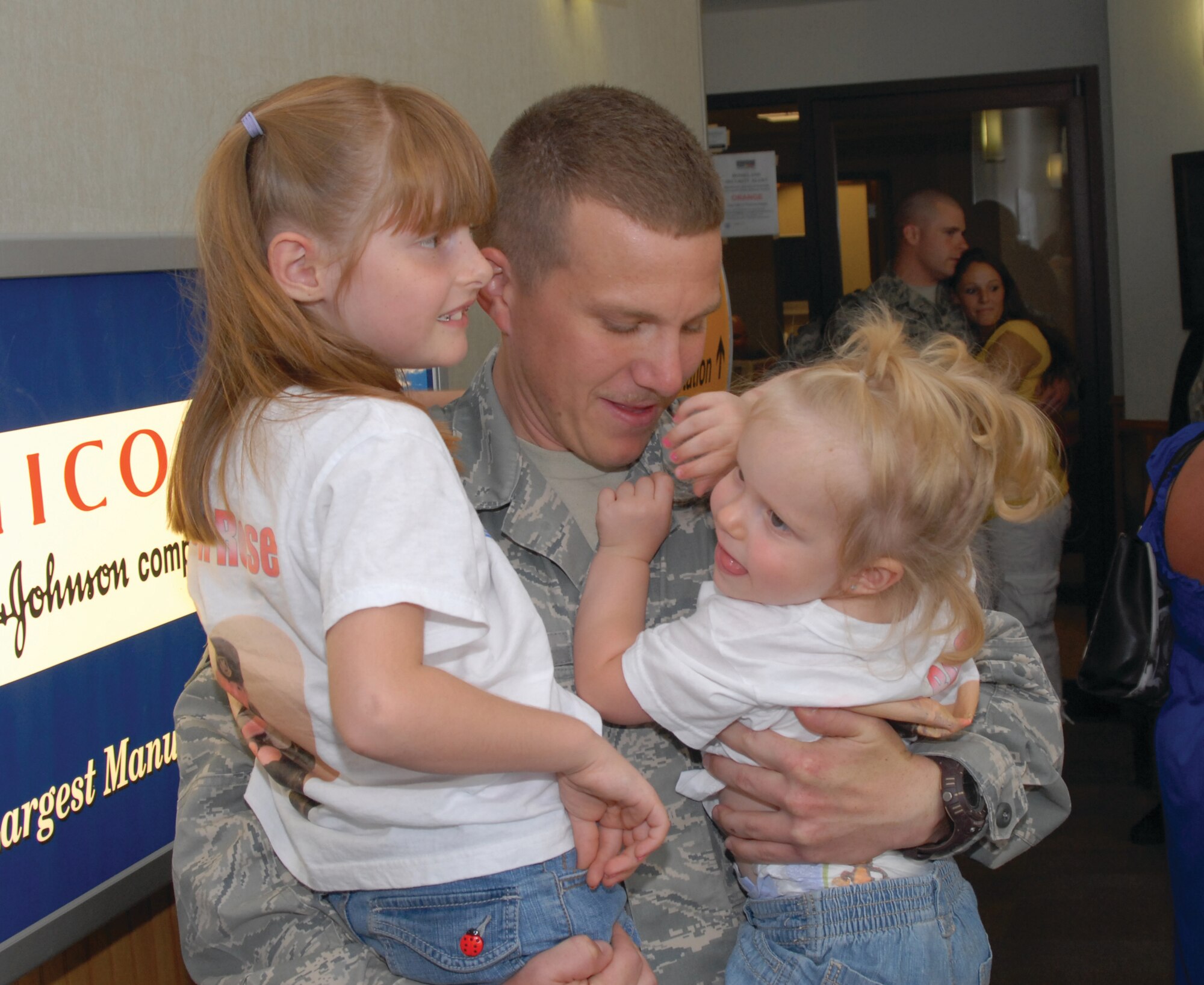 Airman First Class Mikeal Rose, 17th Security Forces Squadron, gets reunited with his daughters on Aug. 21, after returning home from a deployment with 12 of his fellow Airmen. (U.S. Air Force by Robert D. Martinez))