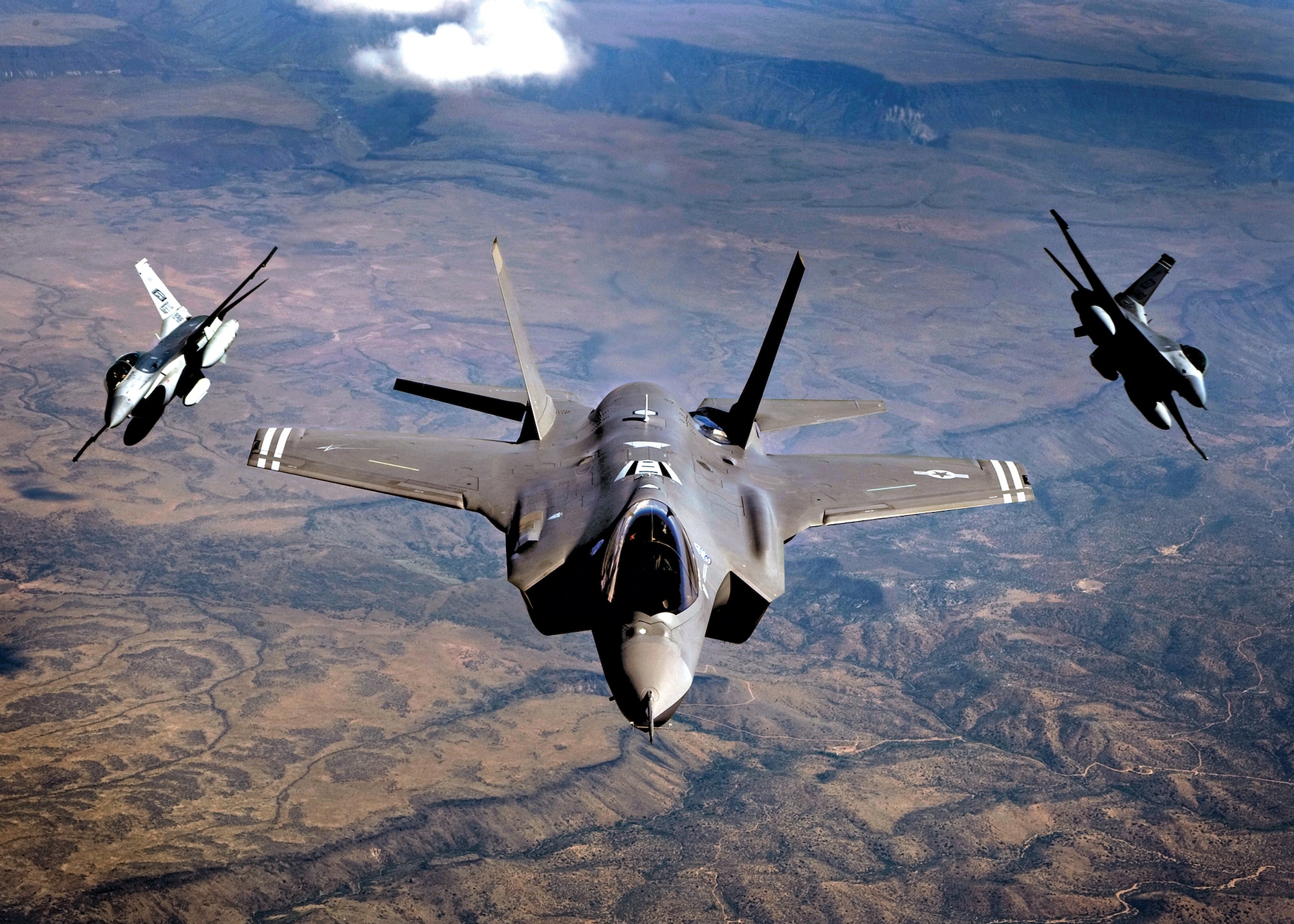 An F-35 Lightning II (middle) and F-16 Fighting Falcons fly to Edwards Air Force Base, Calif. The Lightning II features the most powerful integrated sensor package of any fighter aircraft to date. This package allows the pilot to see a 360-degree view of the battlefield, meaning they have unparalleled information gathering capabilities.  (courtesy photo/Darin Russell)