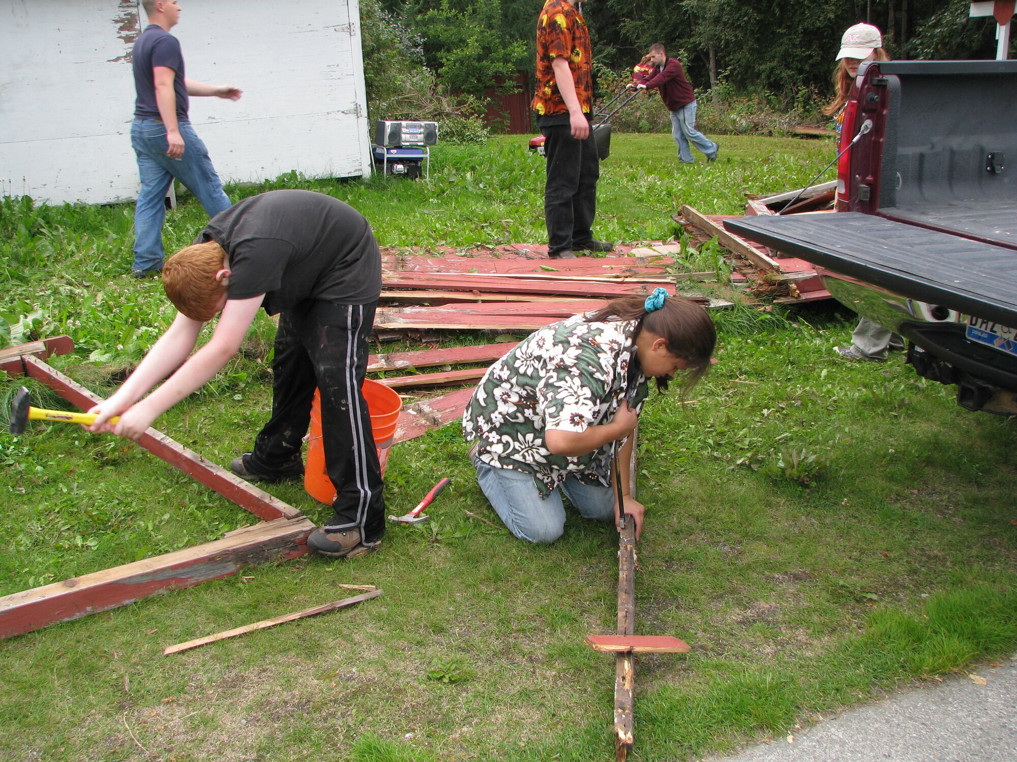 ELMENDORF AIR FORCE BASE, Alaska -- The volunteer group finishes demolishing and removing nails from the remnants of the old fence and begins mowing the back yard and starting demolition of the porch. The group gave their free time on Aug. 23 and 24 to help out an Air Force Guardsman and her family. (courtesy photo)