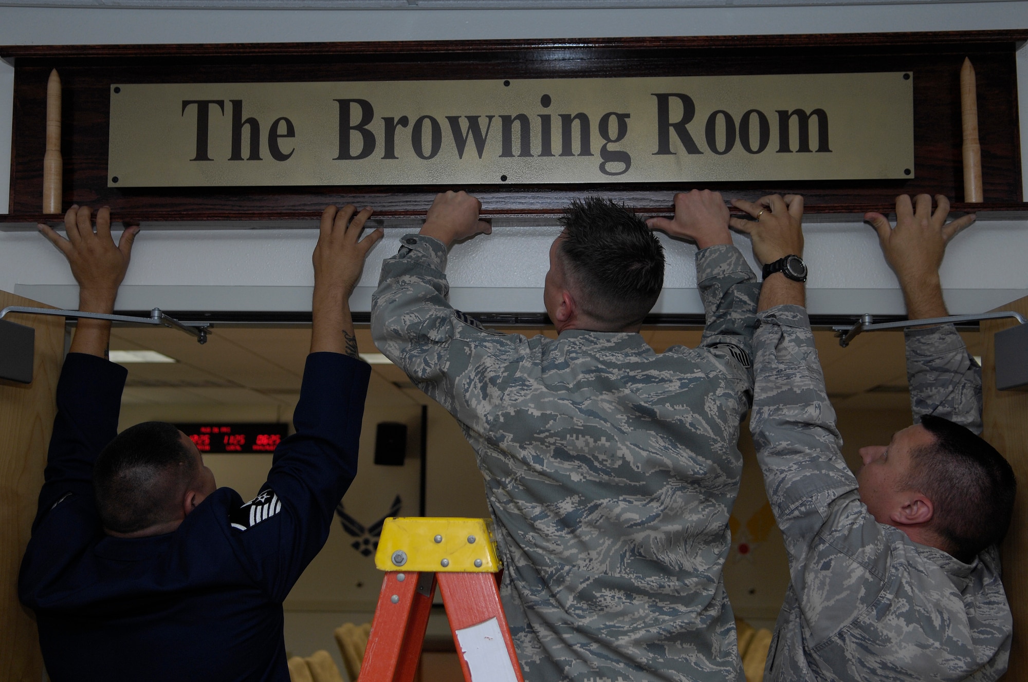 VANDENBERG AIR FORCE BASE, Calif. --  Members of the 576th Flight Test Squadron here place the official Browning Room sign above the door during a ceremony at the 576th FLTS building here Aug. 21. The squadron dedicated the conference room to retired Lt. Col. Jerry Browning. After 30 years active duty, Mr. Browning worked in the 576th FLTS for six years. (U.S. Air Force photo/Airman 1st Class Andrew Lee)