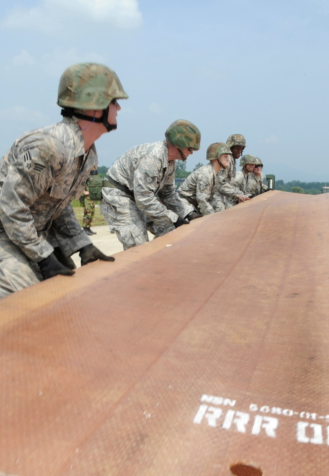 Airmen from the 51st Civil Engineer Squadron unfold a fiberglass mat on the simulated runway before it is put into place Aug. 19 at Jungwon Air Base, South Korea. The 30-foot long, 54-foot wide foot mats are used to quickly repair runway damage, and can be connected to cover a large area. The mats are being moved as part of a joint combined rapid runway repair training exercise with Airmen from the South Korean air force's 19th Tactical Fighter Wing and 91st Air Civil Engineer Group. The 51st CES Airmen are assigned to Osan Air Base, South Korea. (U.S. Air Force photo/Senior Airman Stephenie Wade)