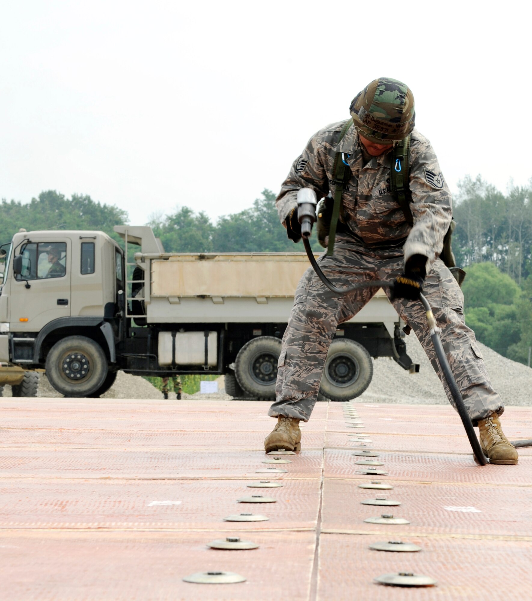 Staff Sgt. William Deguzman uses an air compressor to connect two folded fiberglass mats together on a simulated runway Aug. 19 at Jungwon Air Base, South Korea. The 30-foot long, 54-foot wide foot mats are used to quickly repair runway damage, and can be connected to cover a large area. This process was part of a joint combined rapid runway repair training exercise with Airmen from the South Korean air force's 19th Tactical Fighter Wing and 91st Air Civil Engineer Group. Sergeant Deguzman is assigned to the 51st Civil Engineer Squadron at Osan Air Base, South Korea. (U.S. Air Force photo/Senior Airman Stephenie Wade)