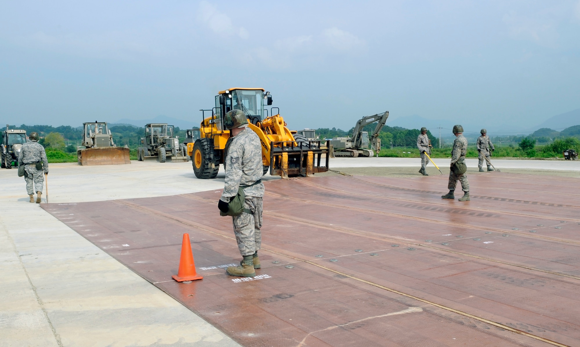 Airmen from the 51st Civil Engineer Squadron stand on a folded fiberglass mat as it is moved into place by a 10,000-pound forklift on a simulated runway at Jungwon Air Base, Republic of Korea, Aug. 19. The 30-foot long, 54-foot wide mats are used to quickly repair runway damage, and can be connected to cover a large area. The mats are being moved as part of a joint combined rapid runway repair training exercise with Airmen from the South Korean air force's 19th Tactical Fighter Wing and 91st Air Civil Engineer Group. The 51st CES is assigned to Osan Air Base, South Korea. (U.S. Air Force photo/Senior Airman Stephenie Wade)
