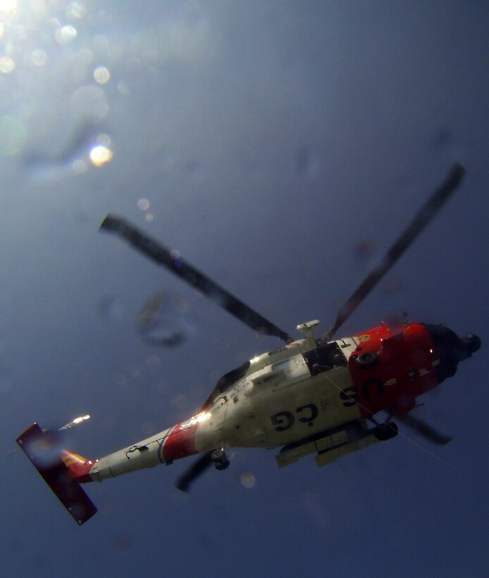 LANGLEY AIR FORCE BASE, Va. -- A MH-60J Jayhawk flies over the water to hoist Survival, Evasion, Resistance and Escape students up from the water during their water survival training here Aug. 25.  The survival training, conducted by SERE specialists, teaches students how to survive if they egress over water. The course also covers proper signaling, desalinating water, finding sustenance and how to properly release from a parachute drag. Pilots are required to complete water survival training every three years. (U.S. Air Force photo/Senior Airman Zachary Wolf)