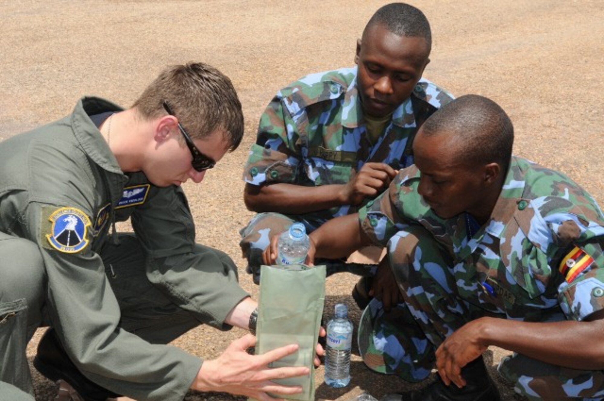 SSgt. Brock Knobloch shows Pvt. Mansur Mupensi (right) and Pvt. Tinkansiimire Happy of the Ugandan People's Defense Air Force how to "cook" a meal-ready-to-eat during a TSC event Aug. 26 in Entebbe, Uganda. (U.S. Air Force photo by Maj. Paula Kurtz.)