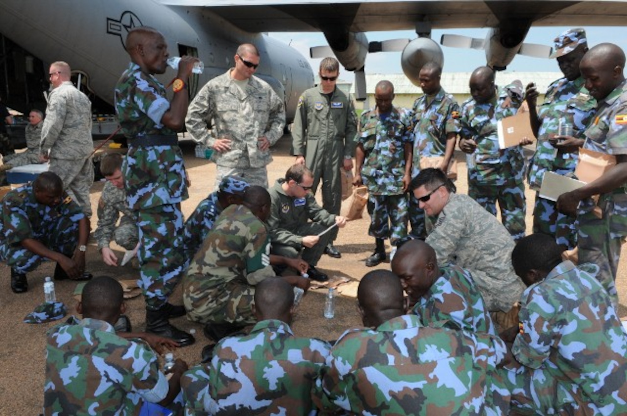 SSgt. Josh Woolridge,37th Airlift Squadron loadmaster, and MSgt. Garrick Lewis, drop zone support lead for 17th Air Force, explain how to "cook" meals-ready-to-eat to members of the Ugandan Peoples Defense Forces during a TSC event Aug. 26. (U.S. Air Force photo by Maj. Paula Kurtz.)