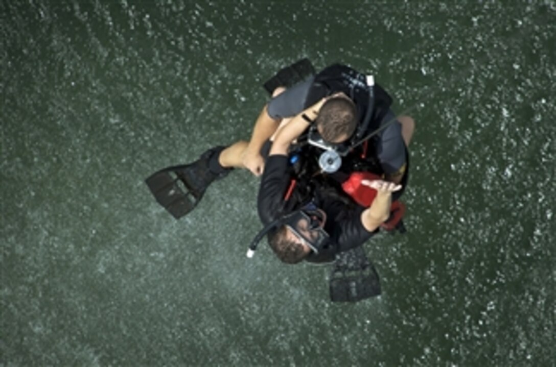 A U.S. Navy aviation rescue swimmer candidate gives the signal to be lifted out of Pensacola Bay and into an SH-60F Seahawk helicopter assigned to Training Air Wing 5 during search and rescue jump training at Naval Air Station Whiting Field in Milton, Fla., on Aug. 19, 2009.  