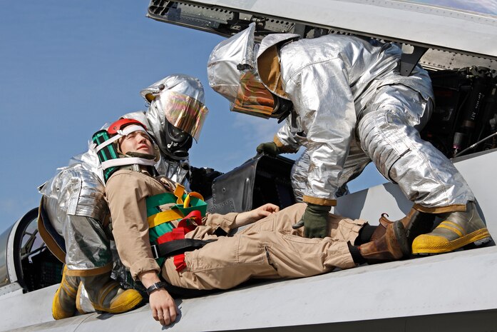 Two Aircraft Rescue Firefighter Marines work together to safely carry a simulated injured pilot out of his jet during a training exercise on the flight line here Aug. 27. Proper teamwork was required throughout the exercise so the ARFF Marines could accomplish their mission of saving the pilot’s life.