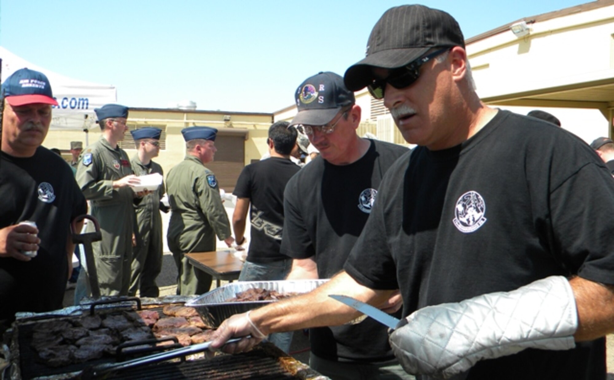 Chief Master Sgt. Stuart Bisland, Master Sgt. Tom Lynch and Tech. Sgt. Brian Kotcher flip steaks on the grill as participant’s line up for food. The 13th Reconnaissance Squadron held a steak burn to raise money for the Airman 1st Class Colton Fund. The squadron raised more than $1900 dollars. (U.S. Air Force Photo/ Dana Lineback)
