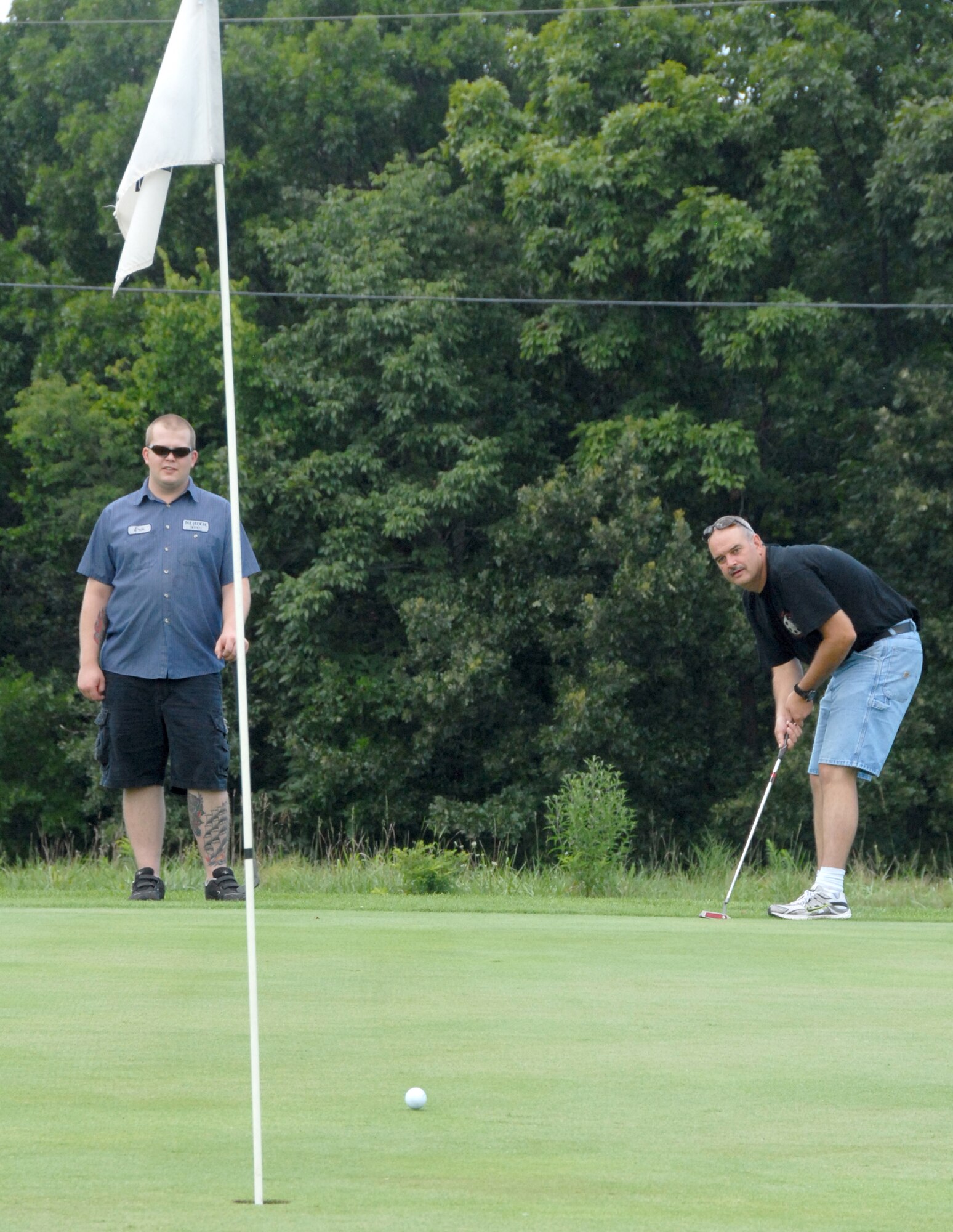 Master Sgt. Mike Butler attempts a long put at hole number six at the Royal Oaks Golf Course, Whiteman Air Force Base, Mo., Aug. 1 as Senior Airman Erik Lof urges the ball into the hole.  Both men, from the 442nd Maintenance Squadron, participated in a charity golf tournament to benefit the Wright Flight program.  Wright Flight is a program to teach kids self determination and goal setting using aviation as its theme.  Many members of the 442nd Fighter Wing volunteer their time for the Wright Flight program through the wing's Human Resources Development Council.  The tournament raised more than $1,500 for the program. The 442nd is an Air Force Reserve wing based at Whiteman. (U.S. Air Force photo/Maj. David Kurle)