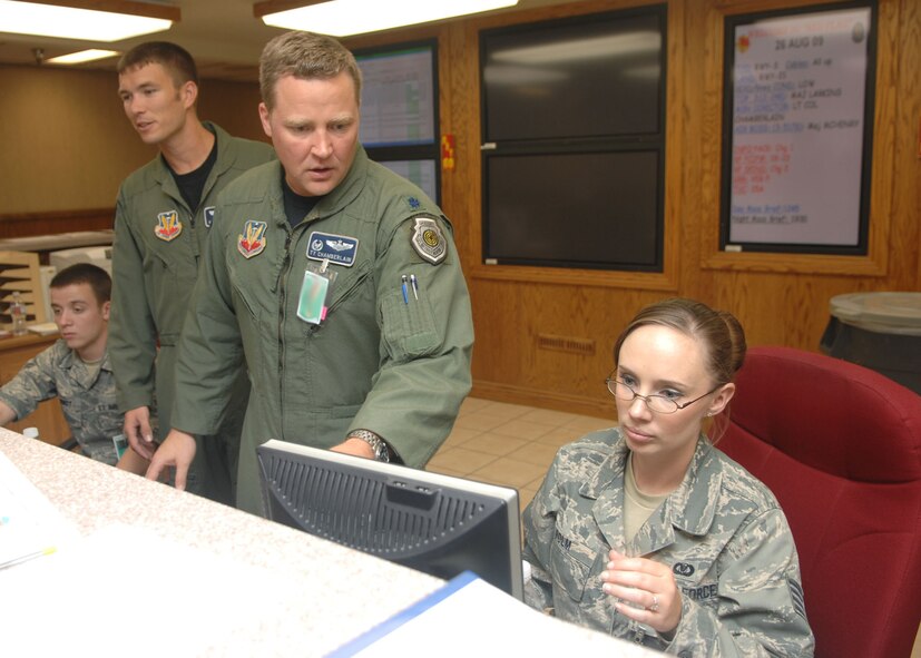NELLIS AIR FORCE BASE, Nev. -- Capt. Warren Carroll, 20th Bomb Squadron, shadows Lt. Col. Tyrell Chamberlain, 20th Bomb Squadron commander, as he goes over the most current information at the Red Flag operations desk with Staff Sgt. Mariah Polm, an Airfield Resource Manager with 34th Fighter Squadron, Hill Air Force Base, Utah. (U.S. Air Force photo by Staff Sgt. Sarah Stegman)