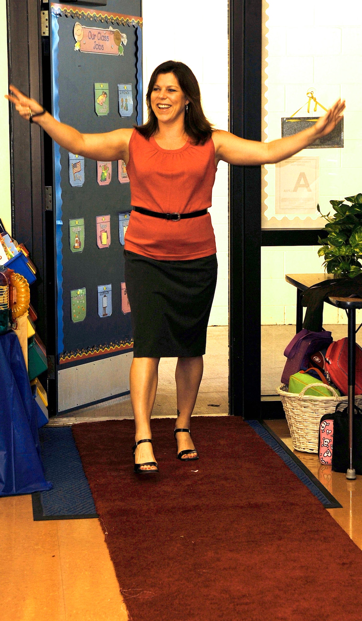 Ms. Jordan Whitcomb, Tinker Elementary third grader teacher, enters with enthusiasm into classroom revealing her new look here Tuesday. Miss Whitcomb was a winner in the Back to School, Back to Style contest put on by Jones New York and Macy's. Along with her shopping spree, miss Whitcomb also received money to put toward her classroom and money for Tinker.  (U.S. Air Force photographer by Senior Airman Nancy Hooks)