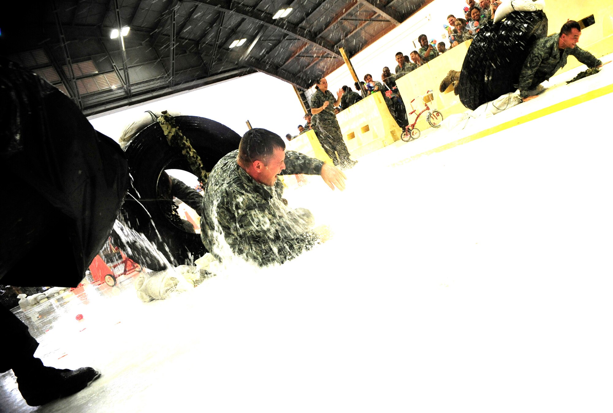 Airmen conduct their journey through the obstacle course at the Enlisted Combat Dining In at Hangar 1 here Aug. 21. Throughout the obstacle course, Airmen undergo a series of challenges, while their peers spray them with water guns and water balloons. The ECDI, designed as a morale booster and stress reliever for the enlisted servicemembers brought together all enlisted ranks for a night of fun and camaraderie.  (U.S. Air Force photo by Airman First Class Rylan Albright/Released)
