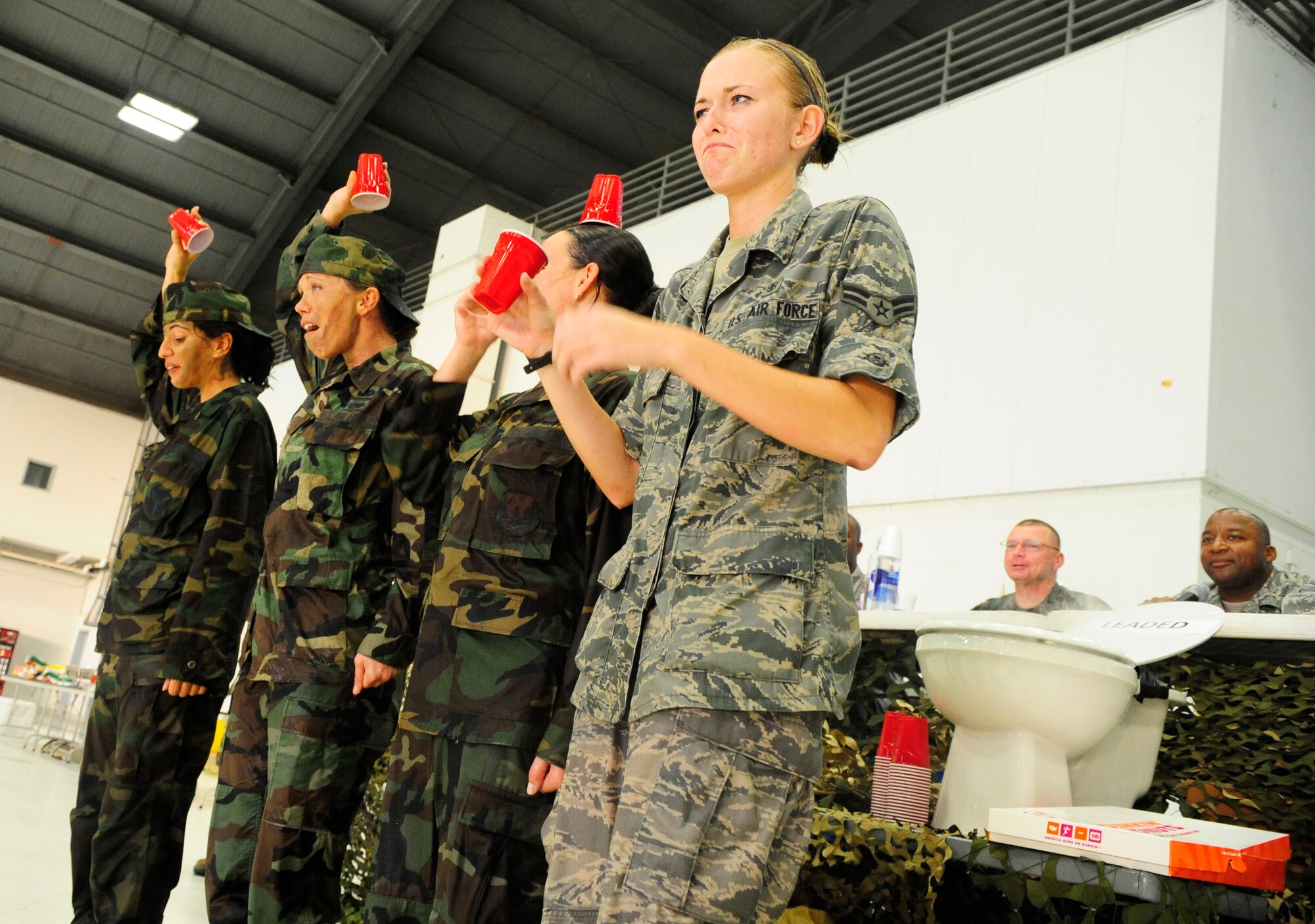 Airmen react after drinking a cup from the "Grog Bowl" during the Enlisted Combat Dining In as Chief Master Sgt. Richard Lee, 6th Mission Support Group superintendant, and Command Chief Master Sgt. Derrick Crowley, 6th Air Mobility Wing Command Chief, look on at Hangar 1 here Aug. 21. The ECDI, designed as a morale booster and stress reliever for the enlisted servicemembers   brought together all ranks for a night of fun and camaraderie.  (U.S. Air Force photo by Airman First Class Rylan Albright/Released)