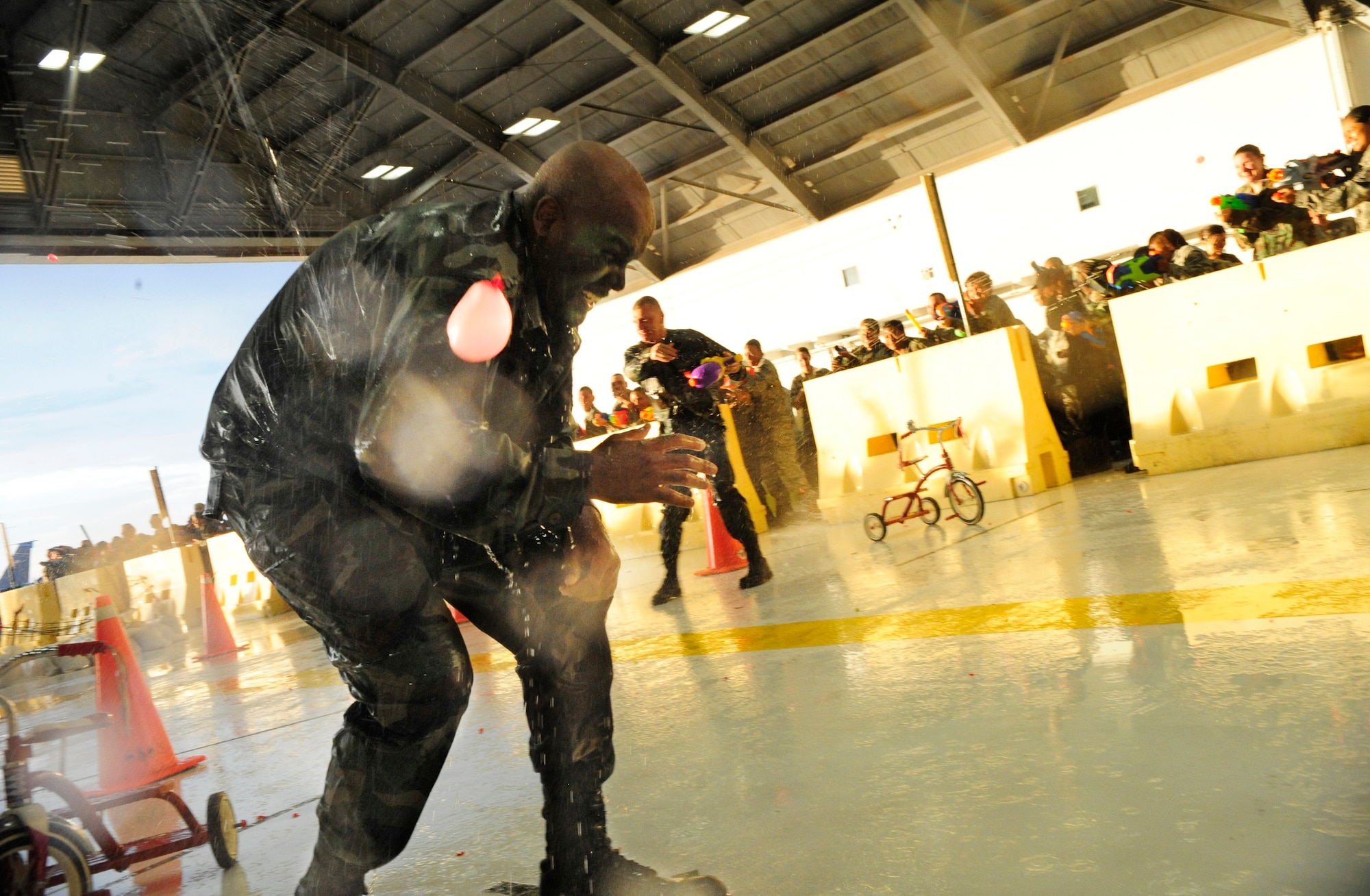 An Airman gets soaked with a water gun midway through his obstacle course journey at the Enlisted Combat Dining In held in Hangar 1 here Aug. 21. Throughout the obstacle course, Airmae undergo a series of challenges, while their peers spray them with water guns and water balloons. The ECDI, designed as a morale booster and stress reliever for the enlisted servicemembers   brought together all ranks for a night of fun and camaraderie.  (U.S. Air Force photo by Airman First Class Rylan Albright/Released)
