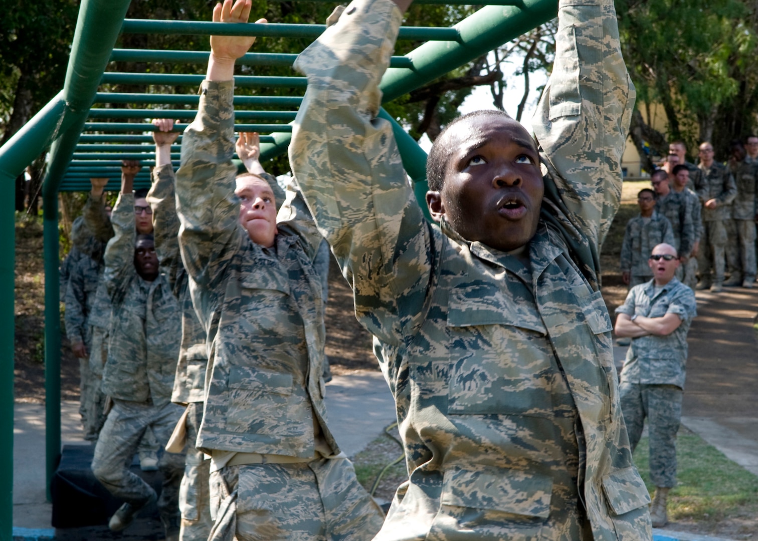 Air Force Basic Military Training trainees focus on the next rung of the monkey bars as they pass over a water filled pit. Trainees complete the obstacle course during their fourth week of training. (U.S. Air Force photo/Benjamin Faske) 