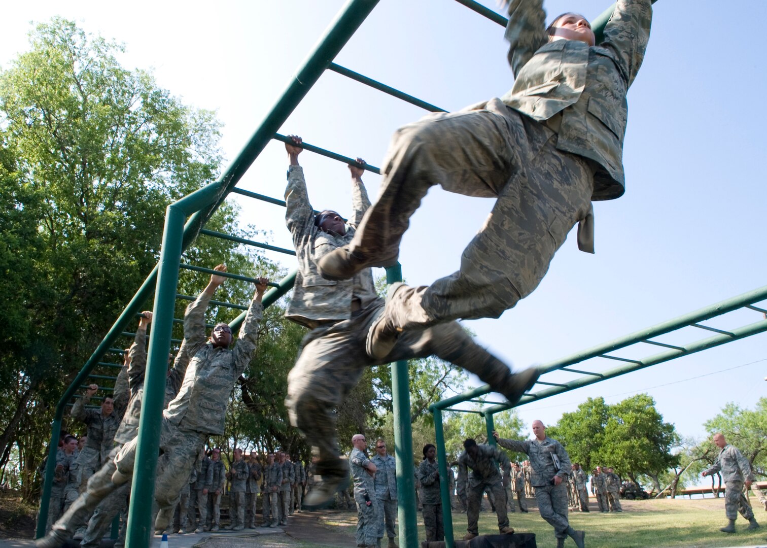 Air Force Basic Military Training trainees swing from the monkey bars as they clear their last obstacle of the day. In BMT, trainees learn the critical importance of discipline, teamwork and foundational knowledge needed to succeed as an Airman. (U.S. Air Force photo/Benjamin Faske)