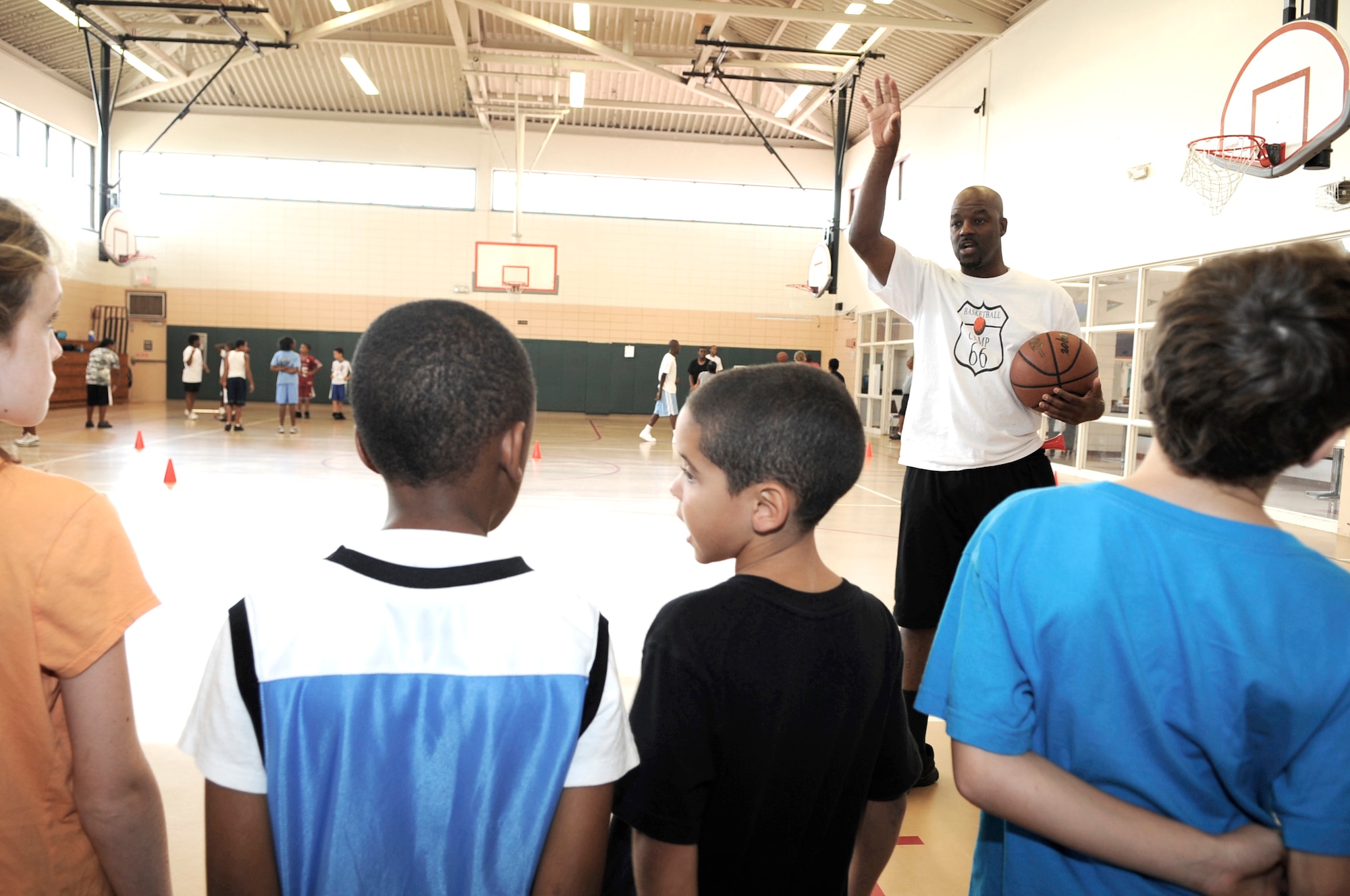 Former Indiana Pacer of the National Basketball League and current NBA Referee Haywoode Workman demonstrates how to follow through after a shot to children of the Basketball Camp 66 at Youth Center here, Aug. 12. Haywoode Workman is hosted the four day basketball camp that more than 60 children of the youth center attended. (US  Air Force Photo By: Senior Airman Angela Ruiz) (Released By: 6th Air Mobility Wing/ Public Affairs Office, )
