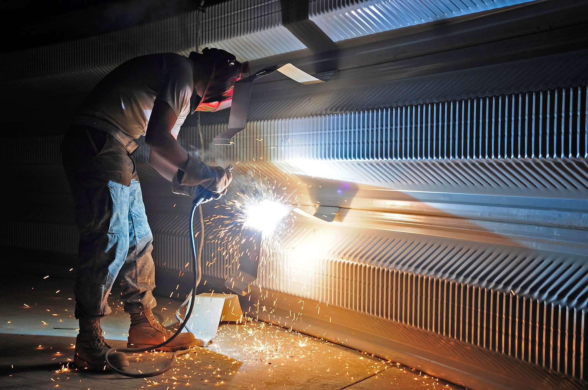 ALI BASE, Iraq - U.S. Air Force Airman 1st Class Robert Campbell Jr., 557th Expeditionary Red Horse Squadron, uses a welder to modify a K-SPAN arch for the new Mine Resistant Ambush Protected (MRAP) armored vehicle rollover trainer here,  Aug. 27, 2009. Airman Campbell is originally from Richford, N.Y., and is deployed here from Malmstrom Air Force Base, Mont. (U.S. Air Force photo / Airman 1st Class Tony R. Ritter)