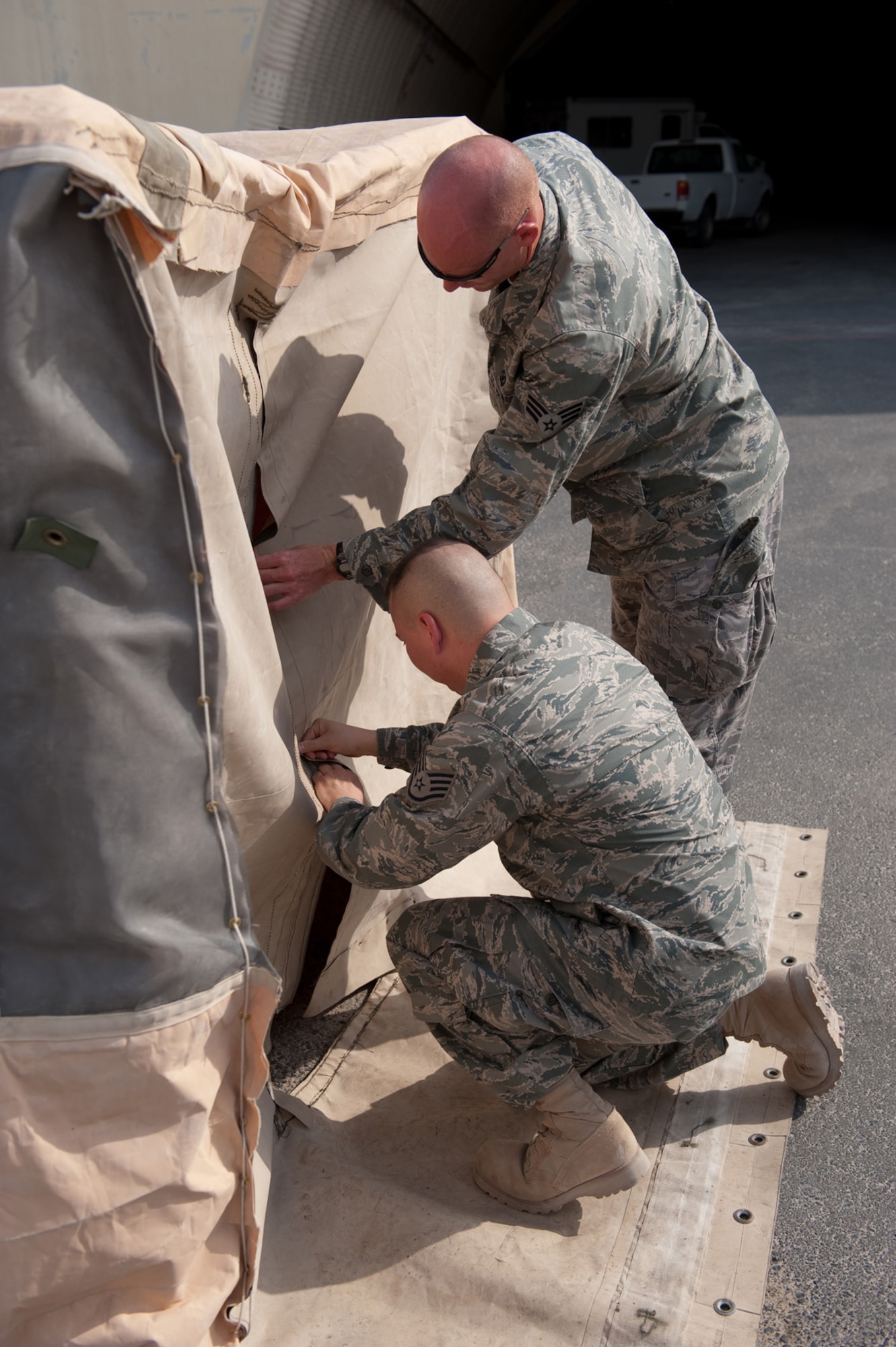 Front, Staff Sgt. Delray Sexton and Senior Airman Shane Shanton, 379th Expeditionary Operations Support Squadron aircrew flight equipment personnel, assemble a custom tent, Aug. 22, in Southwest Asia. The tent is designed to provide shade and respite for flightline maintainers during work-rest cycles in extreme temperatures. Sergeant Sexton is a native of Miami and deployed from Holloman Air Force Base, N.M. Airman Shanton is a native of Jackson, Ohio and deployed from Kirtland AFB, N.M. Both servicemembers are deployed in support of Operations Iraqi and Enduring Freedom. (U.S. Air Force Photo/ Staff Sgt. Robert Barney) 