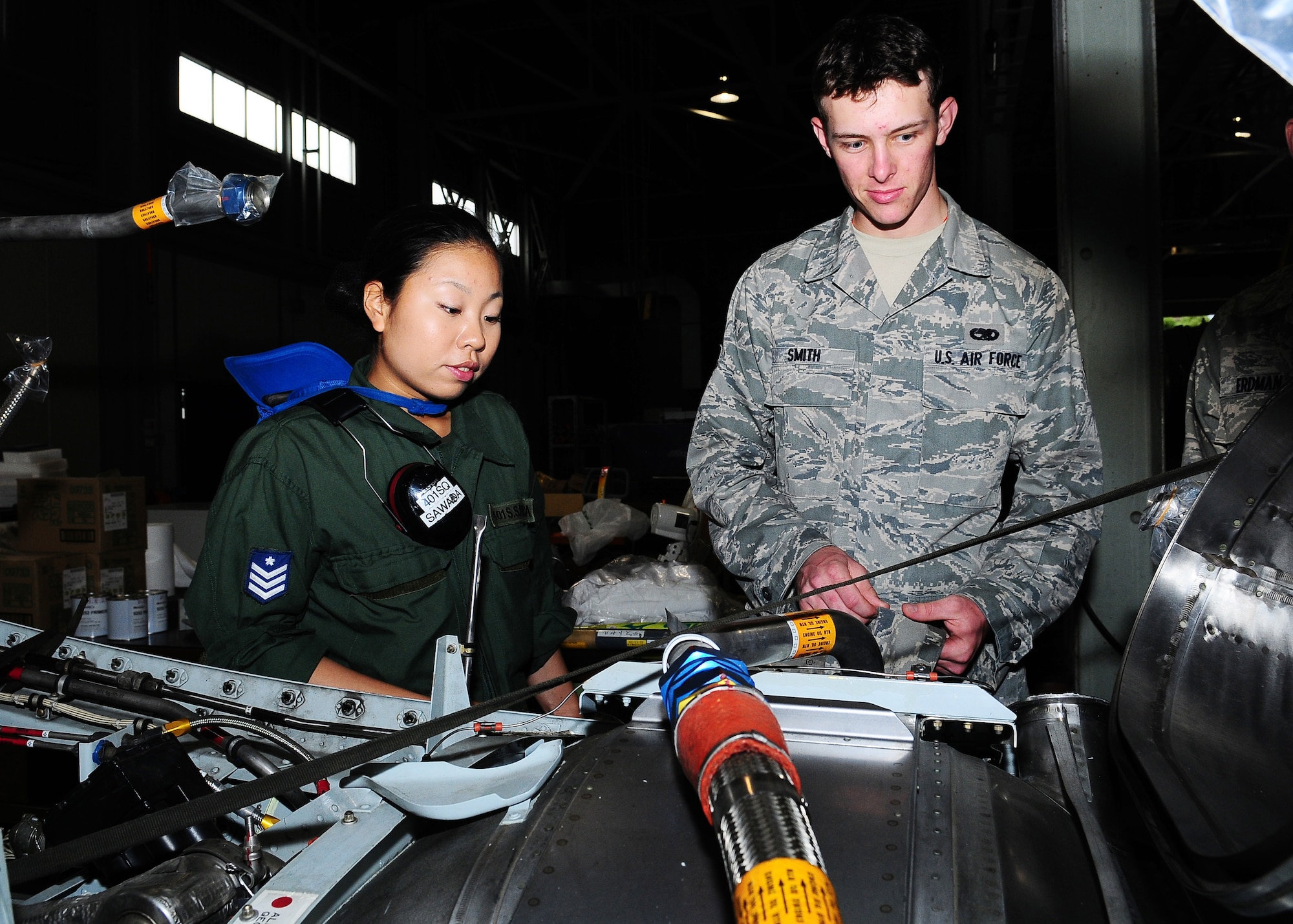 KOMAKI AIR BASE, Japan -- Airman 1st Class Saori Sawada, Japan Air Self-Defense Forces 401st Maintenance Squadron, shows Airman 1st Class Thomas Smith, 374th Maintenance Squadron at Yokota Air Base, Japan, the inside of a JASDF C-130 Hercules' engine during a Bilateral Airlift Training Program visit Aug. 26. The program is designed to enhance interoperability, build working relationships, and explore joint training/operations opportunities. During the visit, Yokota Airmen flew aboard two JASDF C-130s while maintainers toured the base's ground facilities. (U.S. Air Force photo/Airman 1st Class Sean Martin)