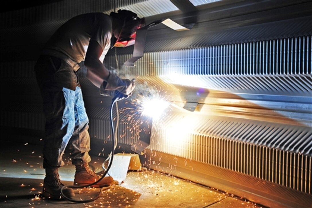 U.S. Air Force Airman 1st Class Robert Campbell Jr. uses a welder to modify a K-span arch for the new mine-resistant, ambush-protected armored vehicle rollover trainer on Ali Base, Iraq, Aug. 27, 2009. Campbell is assigned to the 557th Expeditionary Squadron.